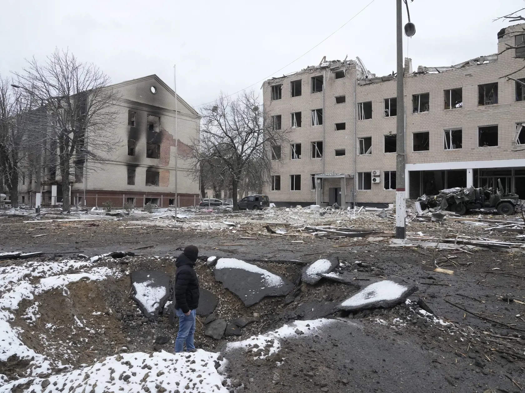 KK50 Brovary - Dobrovoľník jednotiek územnej obrany ukrajinskej armády stojí v kráteri po explózii neďaleko zničenej ubytovne v ukrajinskom meste Brovary nv utorok 1. marca 2022.
