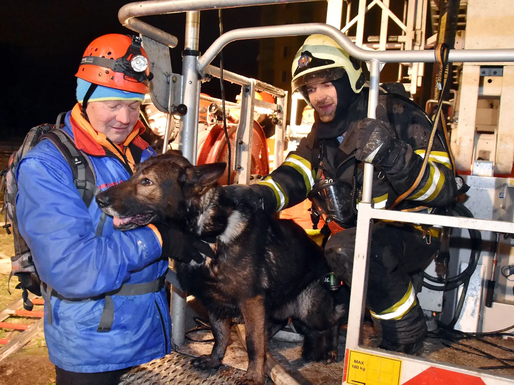 Pri záchranných prácach v zrútenom bytovom panelovom dome pomáhali aj členovia Horskej záchrannej služby so špeciálne vycvičenými psami na vyhľadávanie v ruinách. Na snímke dobrovoľný záchranár z Vysokých Tatier Štefan Strachan(vľavo) s nemeckým ovčiakom Zirom po návrate z vysokozdvižnej plošiny spolu s operátorom zariadenia a príslušníkom HaZZ. Prešov, 6. decembra 2019. FOTO TASR - Vladimír Benko