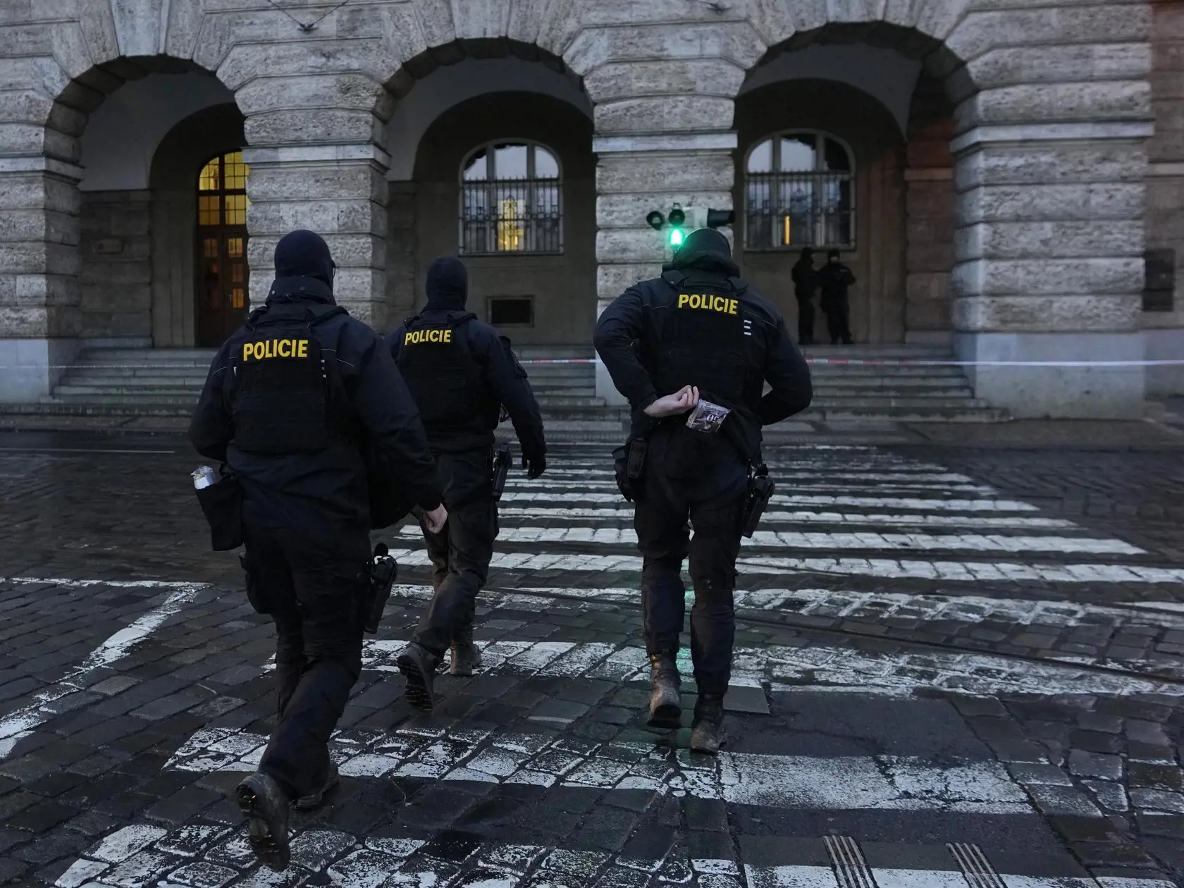 Policajti kráčajú pred budovou Filozofickej fakulty Univerzity Karlovej (FF UK) po streľbe v centre Prahy 22. decembra 2023. Pri streľbe na Filozofickej fakulte Univerzity Karlovej v Prahe prišlo vo štvrtok o život 14 ľudí a 25 je zranených.
