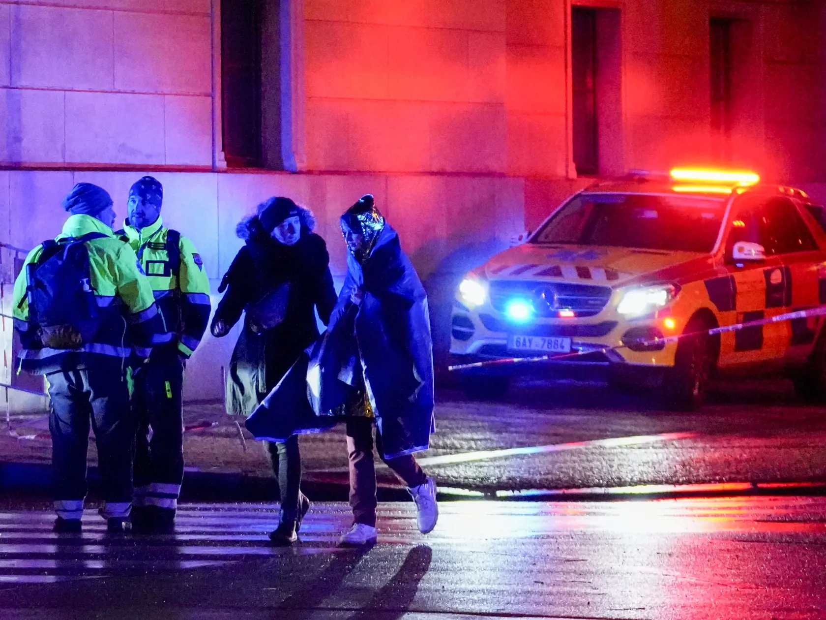 Ľudia kráčajú pri budove Filozofickej fakulty Univerzity Karlovej (FF UK) po streľbe v centre Prahy 21. decembra 2023. Pri streľbe na Filozofickej fakulte Univerzity Karlovej (FF UK) v Prahe prišlo vo štvrtok o život najmenej 15 ľudí a minimálne 24 je zranených. Počet mŕtvych vo štvrtok korigoval český policajný prezident Martin Vondrášek.