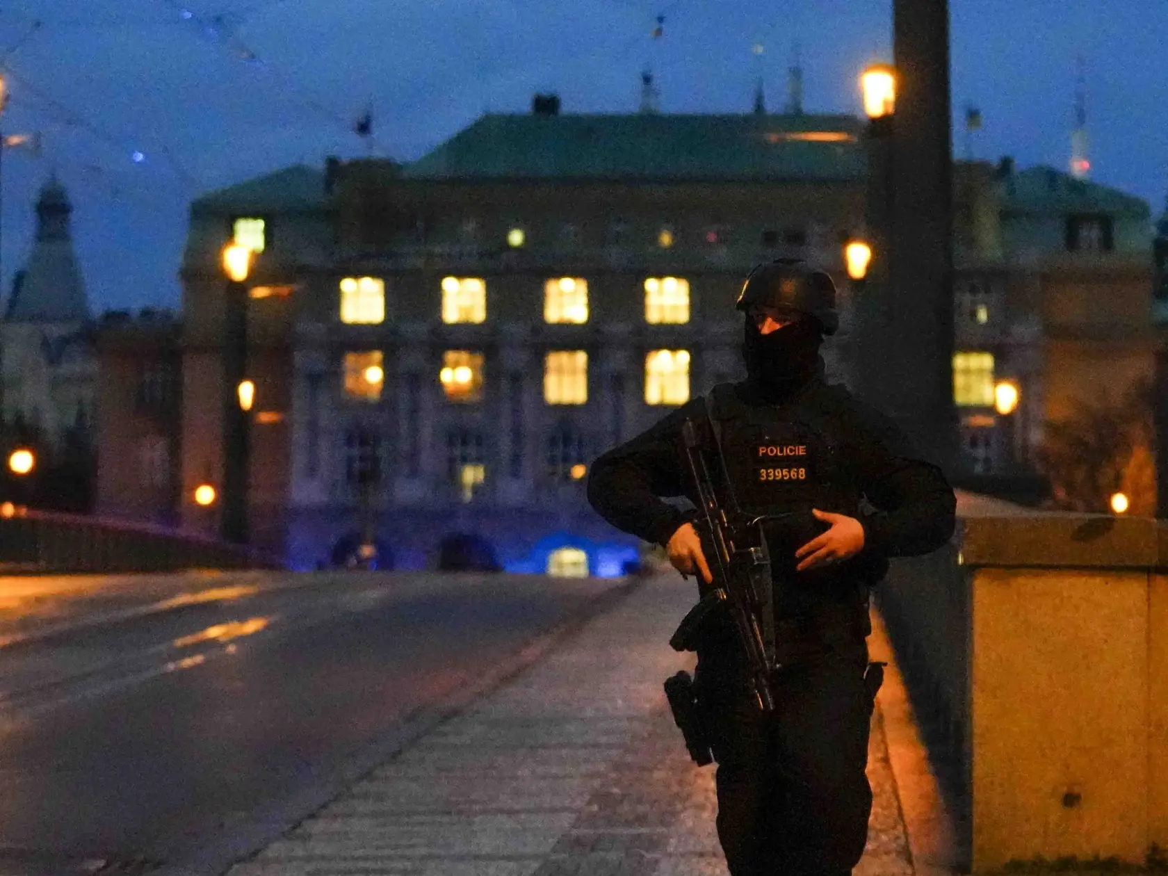 Policajt hliadkuje na moste ponad Vltavu neďaleko budovy Filozofickej fakulty Univerzity Karlovej (FF UK) po streľbe v centre Prahy 21. decembra 2023. Pri streľbe na Filozofickej fakulte Univerzity Karlovej (FF UK) v Prahe prišlo vo štvrtok o život najmenej 15 ľudí a minimálne 24 je zranených.
