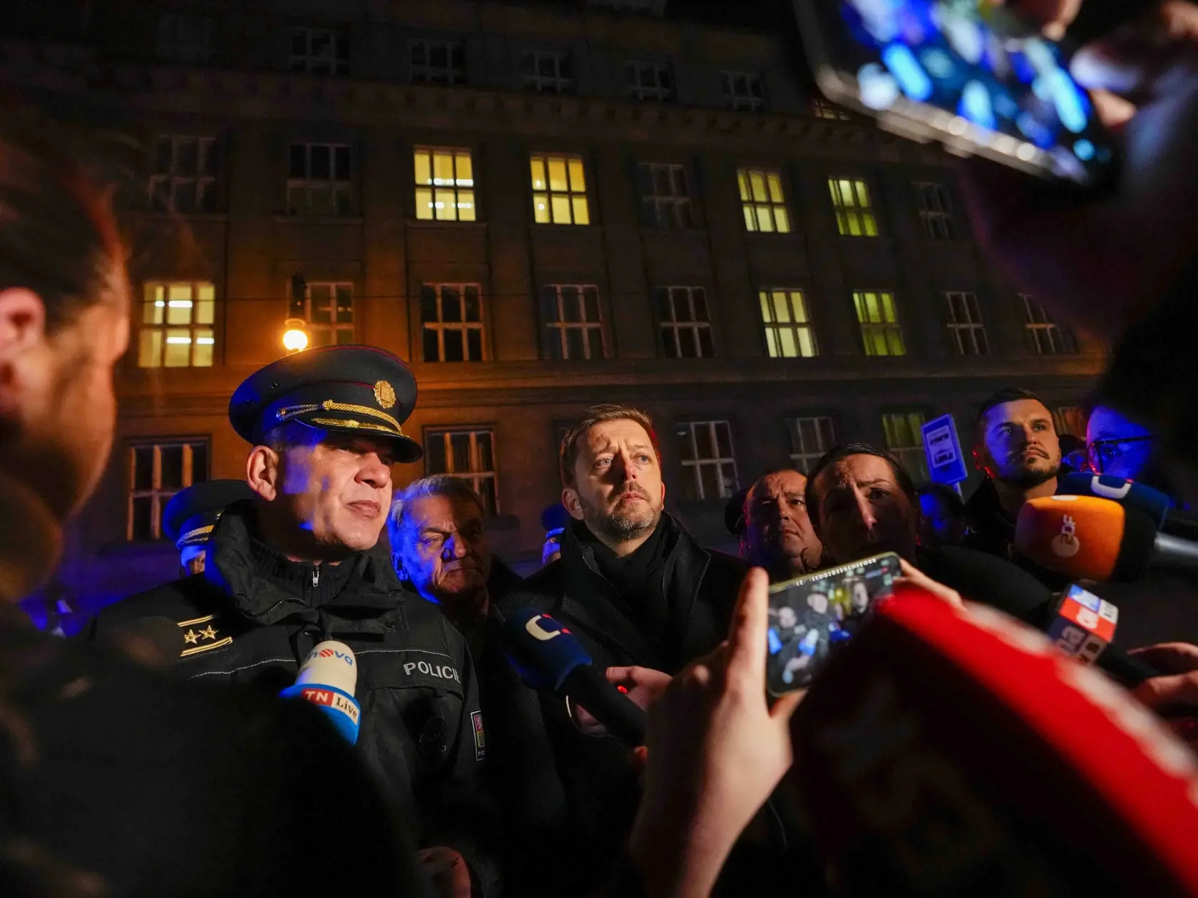 Český minister vnútra Vít Rakušan (uprostred) a policajt Martin Vondrášek (vľavo) hovoria s novinármi po masovej streľbe na Filozofickej fakulte Univerzity Karlovej (FF UK) v centre Prahy 21. decembra 2023. Pri streľbe na Filozofickej fakulte Univerzity Karlovej (FF UK) v Prahe prišlo vo štvrtok o život najmenej 15 ľudí a minimálne 24 je zranených.