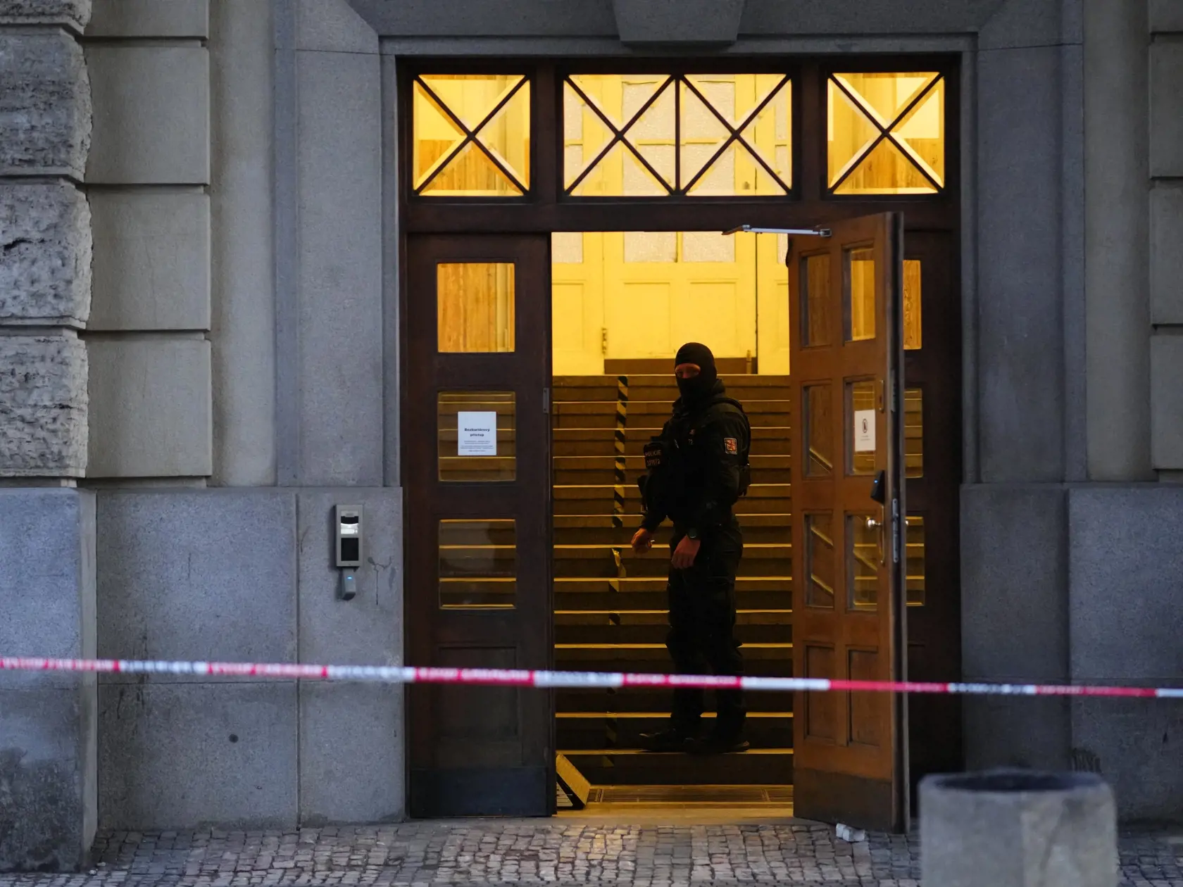 Policajt stojí vo dverách budovy Filozofickej fakulty Univerzity Karlovej (FF UK) po streľbe v centre Prahy 22. decembra 2023. Pri streľbe na Filozofickej fakulte Univerzity Karlovej v Prahe prišlo vo štvrtok o život 14 ľudí a 25 je zranených. Strelec bol podľa polície študentom školy a po útoku zrejme spáchal samovraždu, no strieľali po ňom aj policajti.