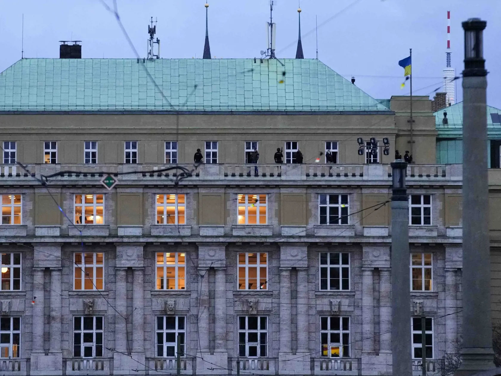 Policajti stoja na balkóne Filozofickej fakulte Univerzity Karlovej (FF UK) po streľbe v centre Prahy 21. decembra 2023. Česká polícia zneškodnila útočníka, ktorý vo štvrtok strieľal v škole v centre Prahy. Uviedla to na sociálnej sieti X. Na mieste je podľa nej niekoľko mŕtvych a desiatky zranených, informuje spravodajkyňa TASR v Prahe.