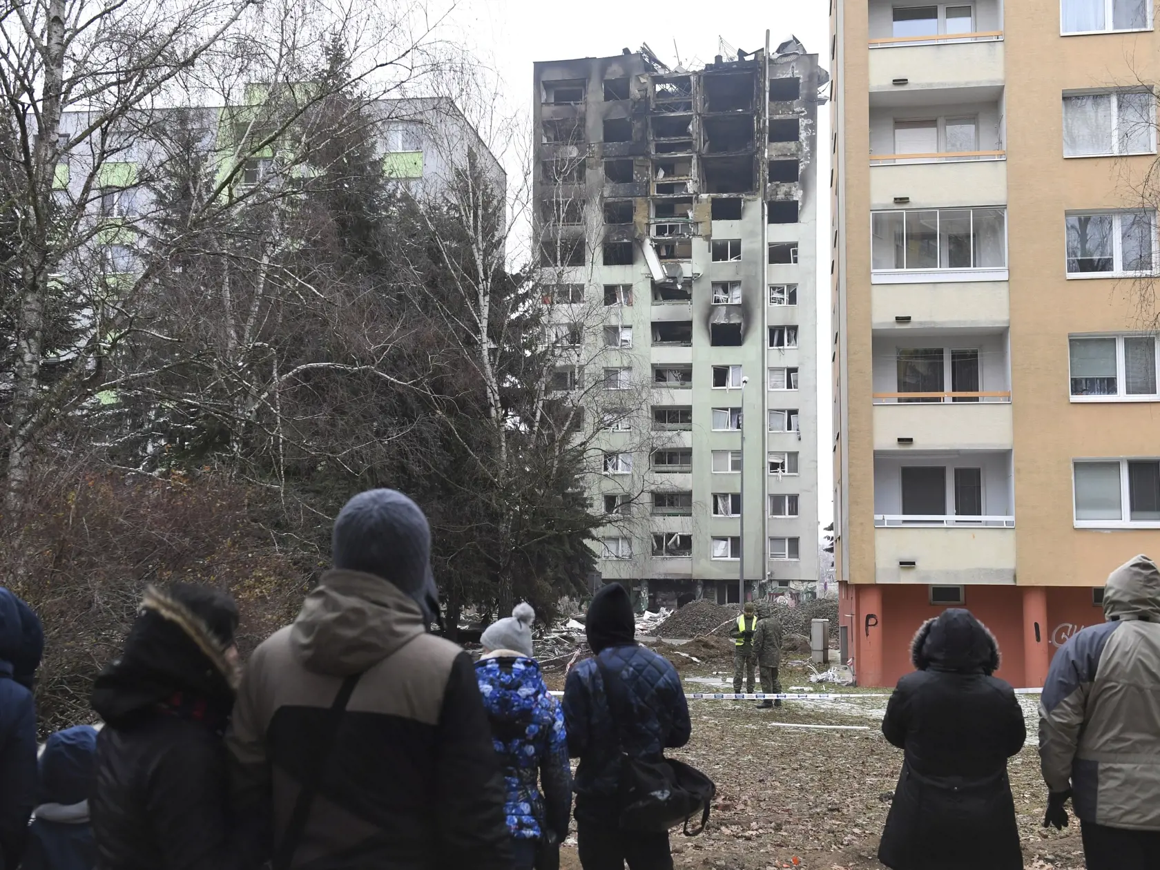Na snímke ľudia sa pozerajú na zhorený bytový dom v Prešove 8. decembra 2019. Požiar mal vzniknúť po výbuchu horných poschodí 12-podlažnej bytovky v piatok pred 12.15 h. FOTO TASR - František Iván