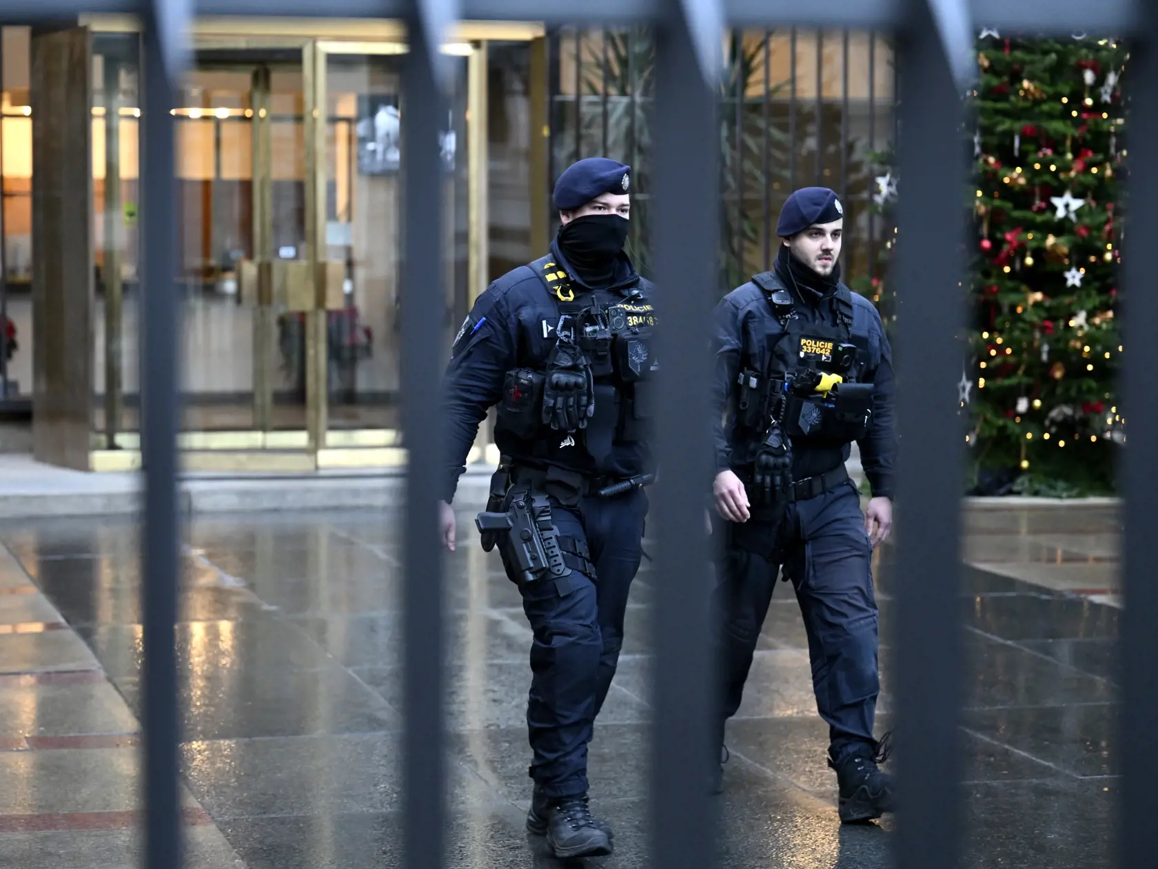 Policajti kráčajú pred budovou Filozofickej fakulty Univerzity Karlovej (FF UK) po masovej streľbe v centre Prahy 22. decembra 2023.