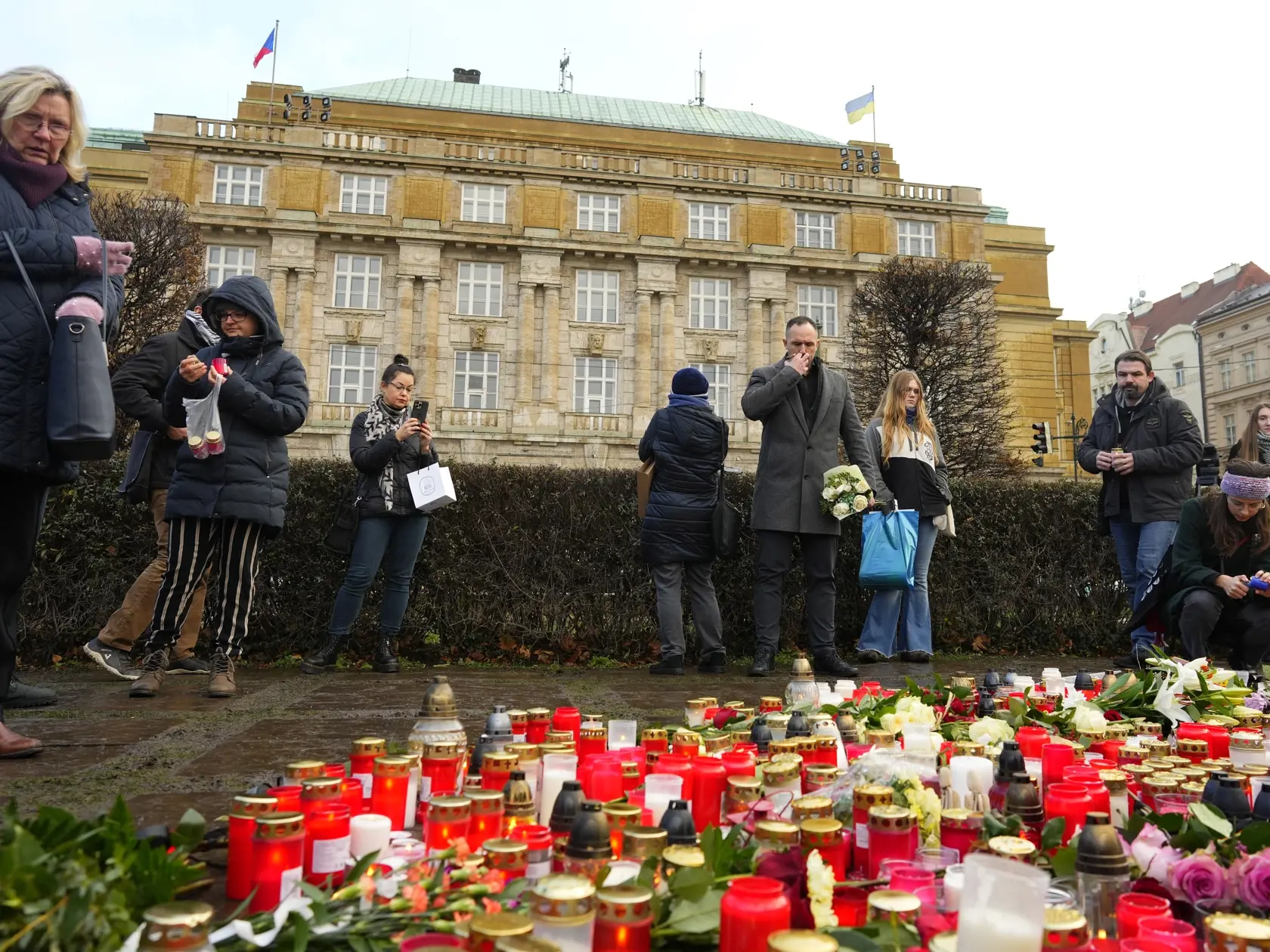 Ľudia zapaľujú sviečky a kladú kvety pred Filozofickou fakultou Karlovej univerzity na pamiatku obetí masovej streľby v centre Prahy v piatok 22. decembra 2023. Pri streľbe na Filozofickej fakulte Univerzity Karlovej v Prahe prišlo vo štvrtok o život 15 ľudí, vrátane strelca. Ďalších  25 osôb utrpelo zranenia. Strelec zasiahol aj troch ľudí v okolí budovy a došlo tiež k prestreleniu civilného vozidla, aj vozidla polície.