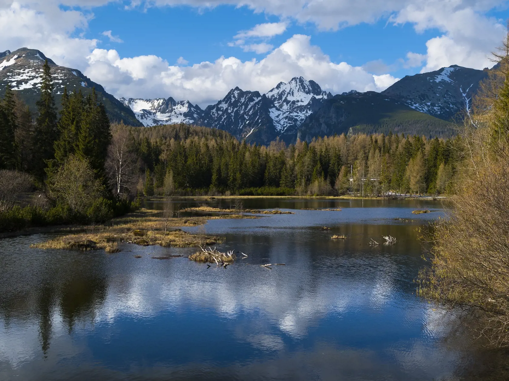 Nové Štrbské pleso pod známejším Štrbským plesom tiež poskytuje pekné pohľady na okolité tatranské štíty. Na snímke vľavo Patria, uprostred Kôpky a masív Vysokej, vpravo Tupá. Štrbské Pleso, 14. mája 2020. FOTO TASR – Milan Kapusta  
