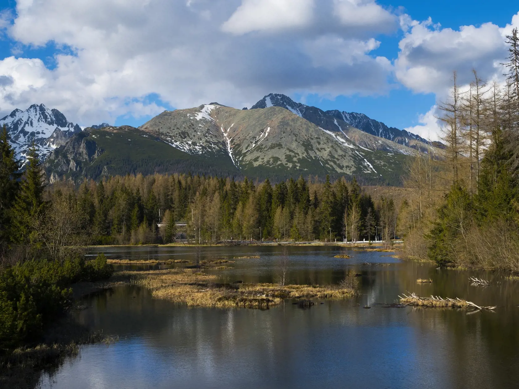 Nové Štrbské pleso pod známejším Štrbským plesom tiež poskytuje pekné pohľady na okolité tatranské štíty. oskytuje pekné pohľady na okolité tatranské štíty. Na snímke vľavo masív Vysokej, uprostred slnkom osvetlená Tupá, za ňou v tieni Končistá a celkom vpravo vzadu masív Gerlachovského štítu. Štrbské Pleso, 14. mája 2020. FOTO TASR – Milan Kapusta  
