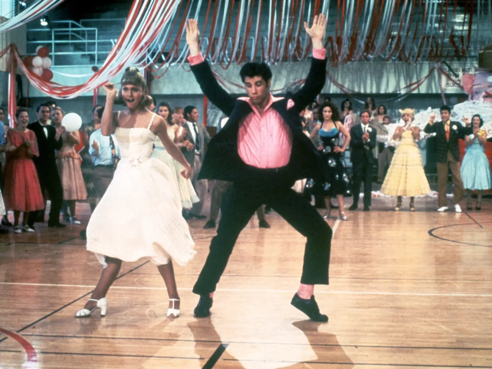 1978:  Australian singer and actor Olivia Newton-John and American actor John Travolta dance in a crowded high school gym in a still from the film, 'Grease,' directed by Randal Kleiser.  (Photo by Paramount Pictures/Fotos International/Getty Images)