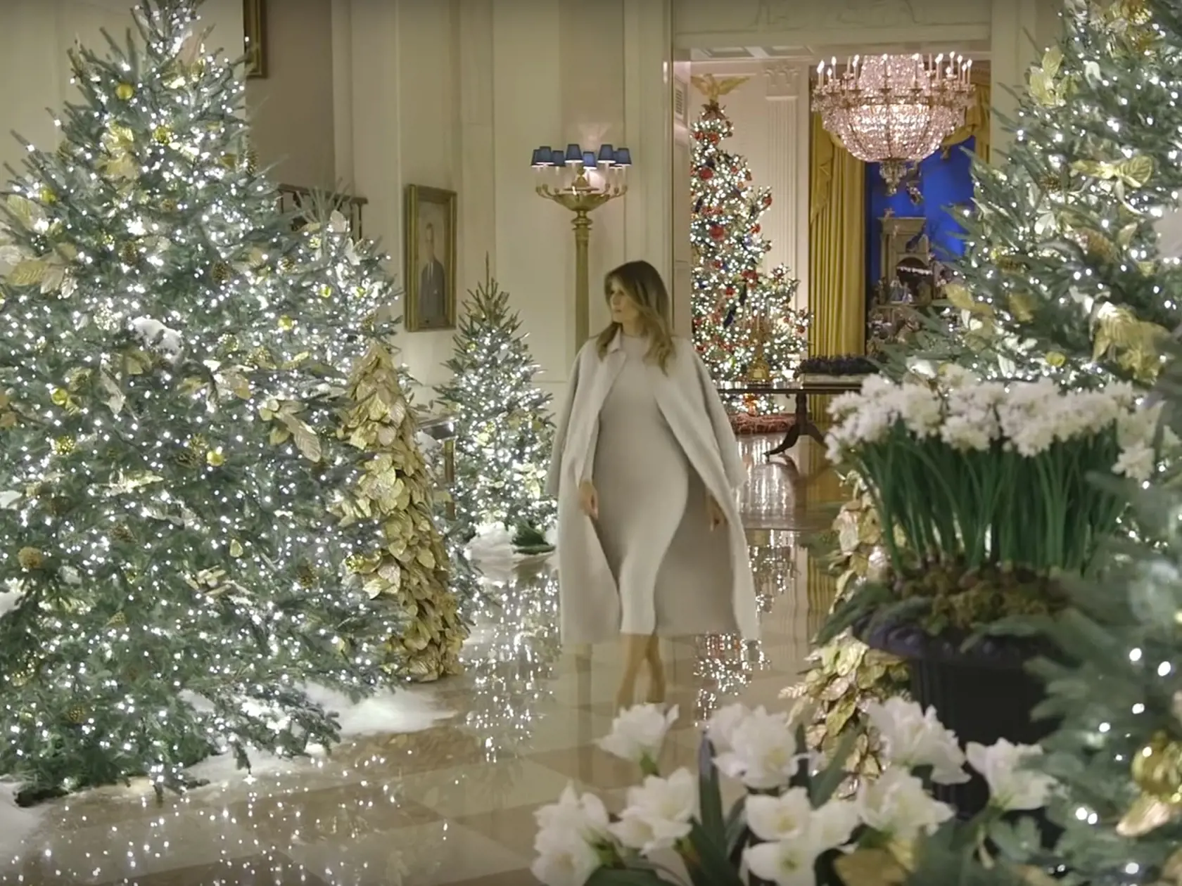 Melanie Trumpová prezentuje vianočný výzdobu Bieleho domu 2019. Siaha po kabáte prehodenom cez plecia, ktorý jej slúži ako barlička.