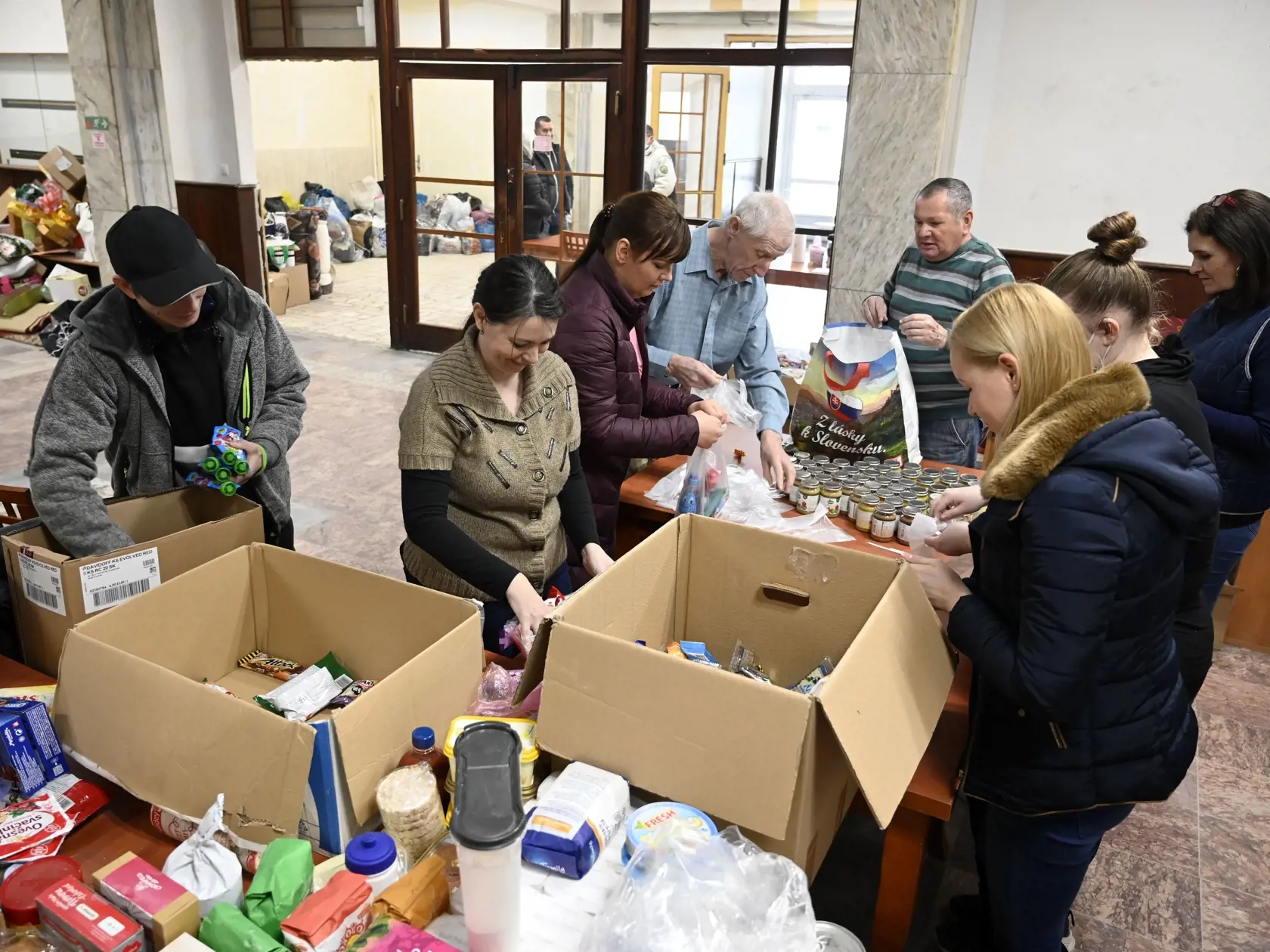 Na snímke balenie potravinových balíčkov v sklade humanitárnej pomoci pre utečencov z Ukrajiny v priestoroch Mestského kultúrneho strediska (MKS) v meste Veľké Kapušany 2. marca 2022. FOTO TASR - Roman Hanc