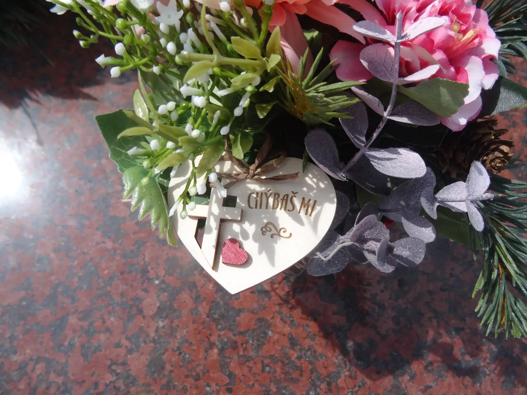 Na hrobe je položená malá ikebana v črepníku so srdiečkom, krížikom a nápisom: "Chýbaš mi!"