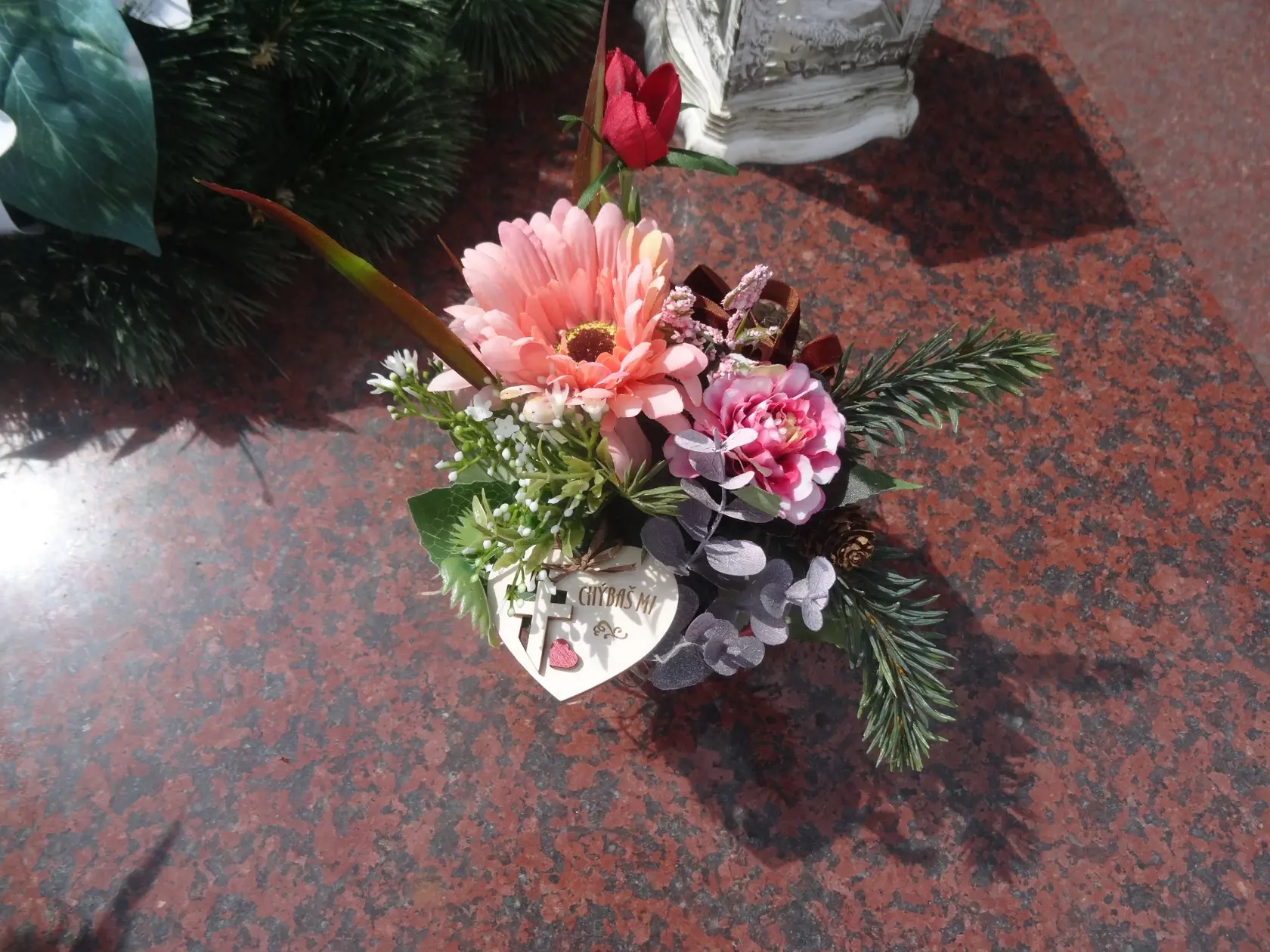 Na hrobe je položená malá ikebana v črepníku so srdiečkom, krížikom a nápisom: "Chýbaš mi!"