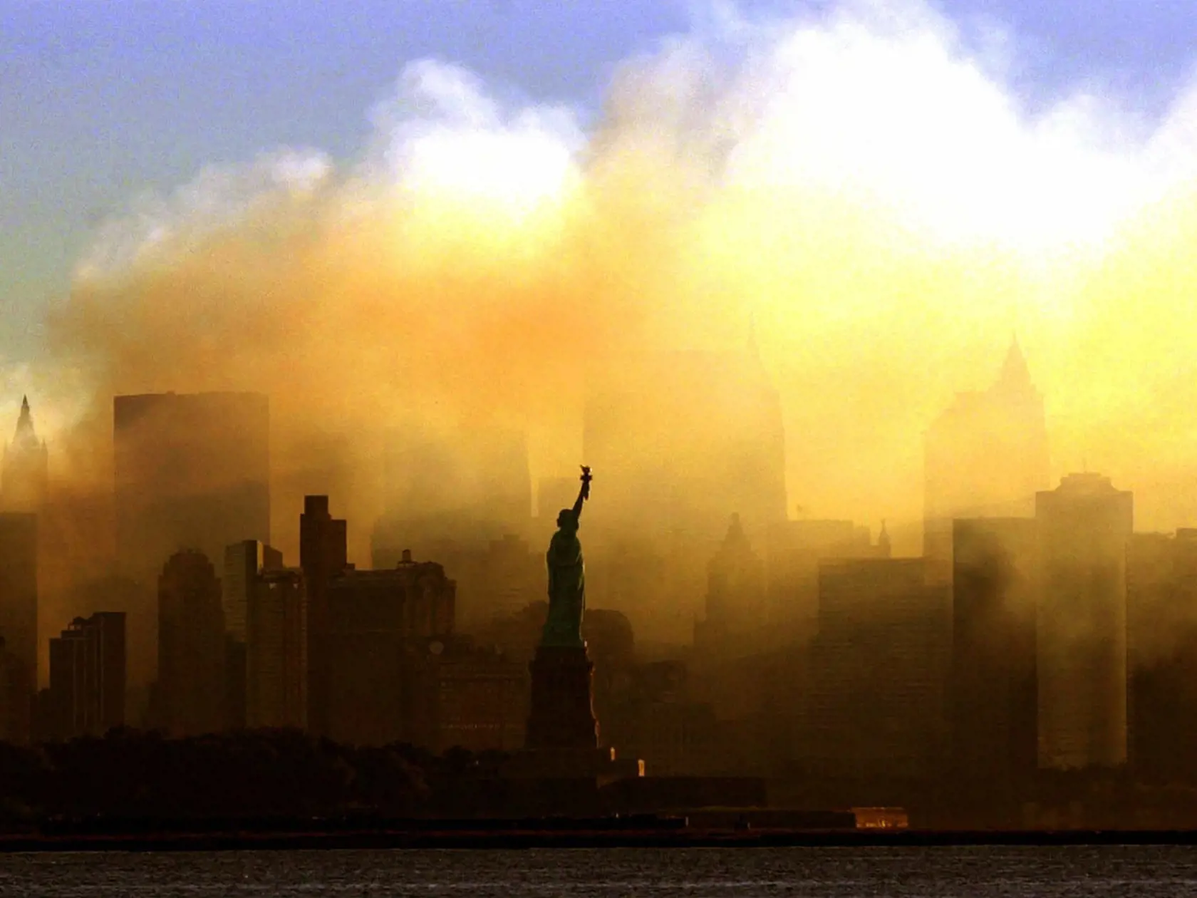 Na archívnej snímke z 15. septembra 2001 Socha slobody stojí pred zadymeným dolným Manhattanom v New Yorku.