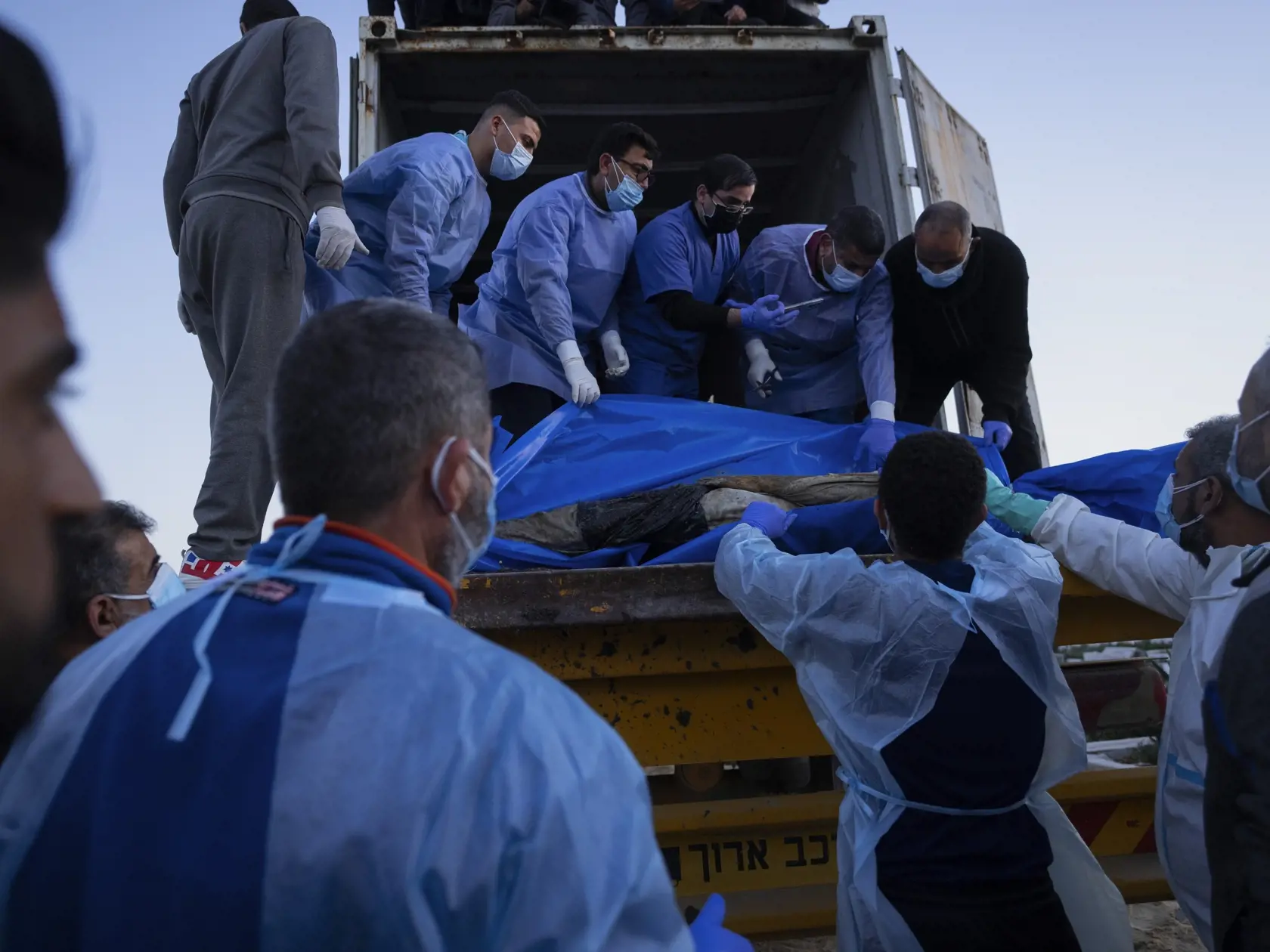 Zdravotníci vykladajú telá Palestínčanov zabitých v bojoch s Izraelom a odovzdaných izraelskou armádou počas hromadného pohrebu v Rafahu v Pásme Gazy v utorok 26. decembra 2023.