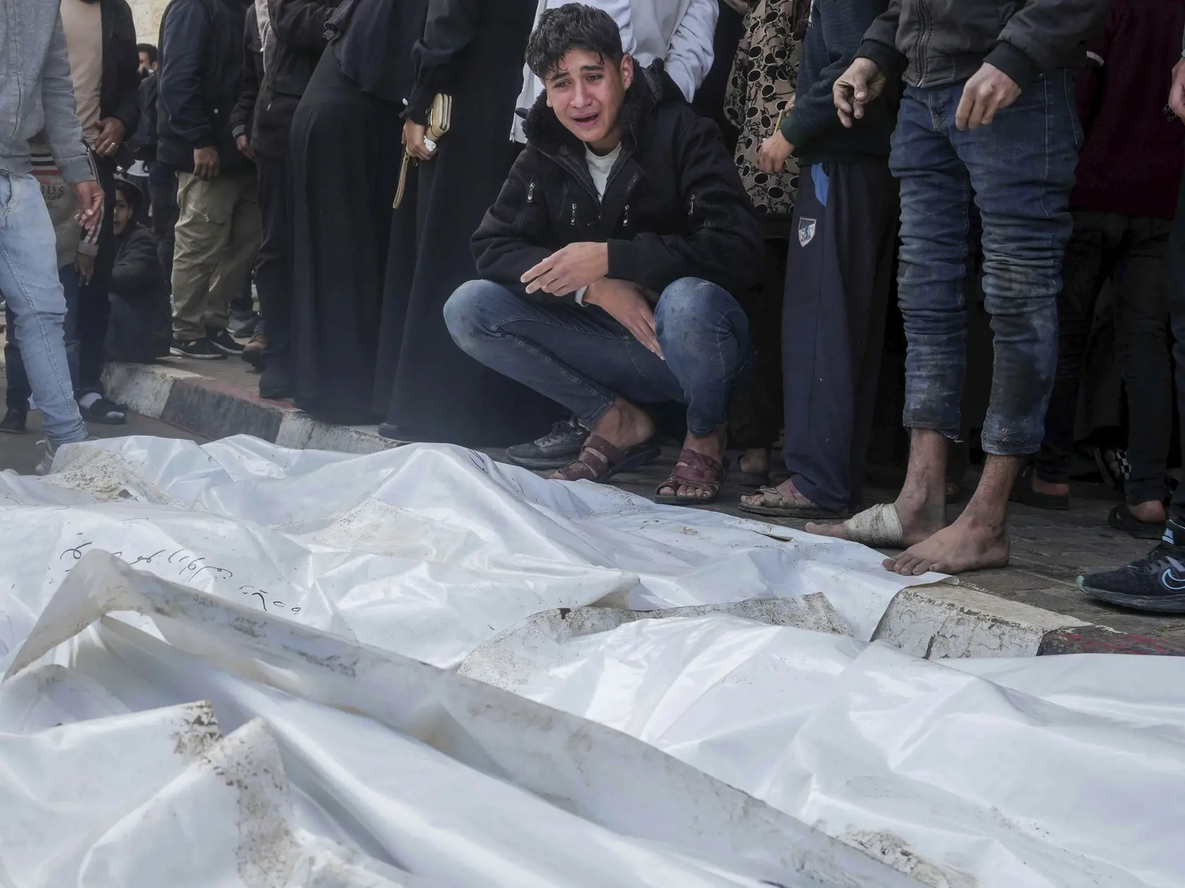 Palestínčania nariekajú nad telami svojich príbuzných, ktorí zahynuli pri izraelskom bombardovaní pásma Gazy v meste Deir Al-Balah 25. decembra 2023.