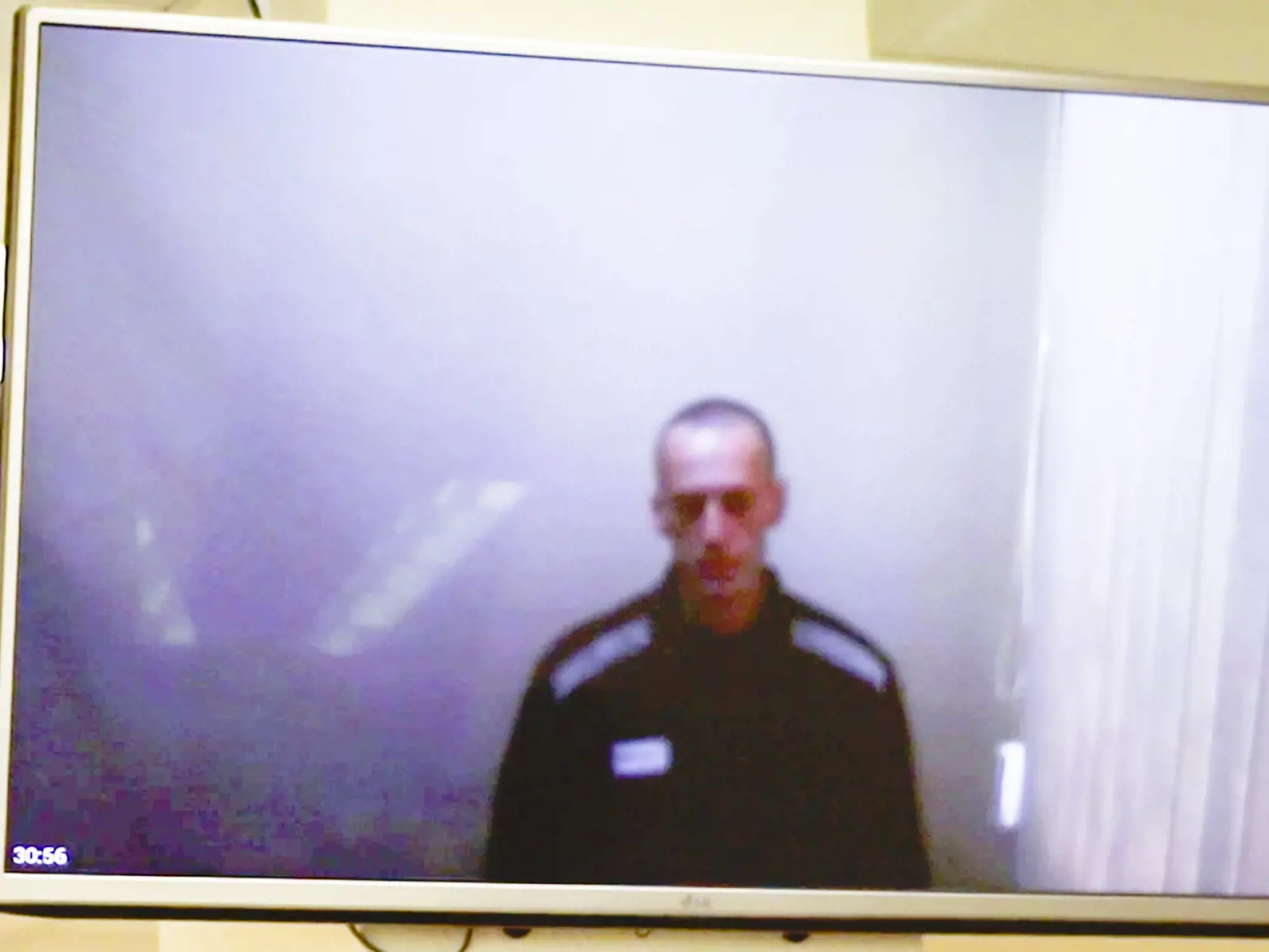 Na snímke z videozáznamu je líder ruskej opozície Alexej Navaľnyj na televíznej obrazovke počas pojednávania o svojich obvineniach na okresnom súde v Moskve v Rusku 29. apríla 2021. V