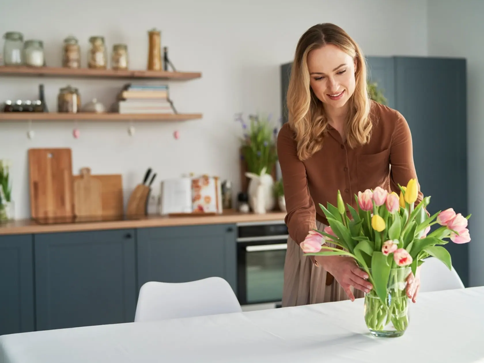 Caucasian woman putting fresh tulips into the vase