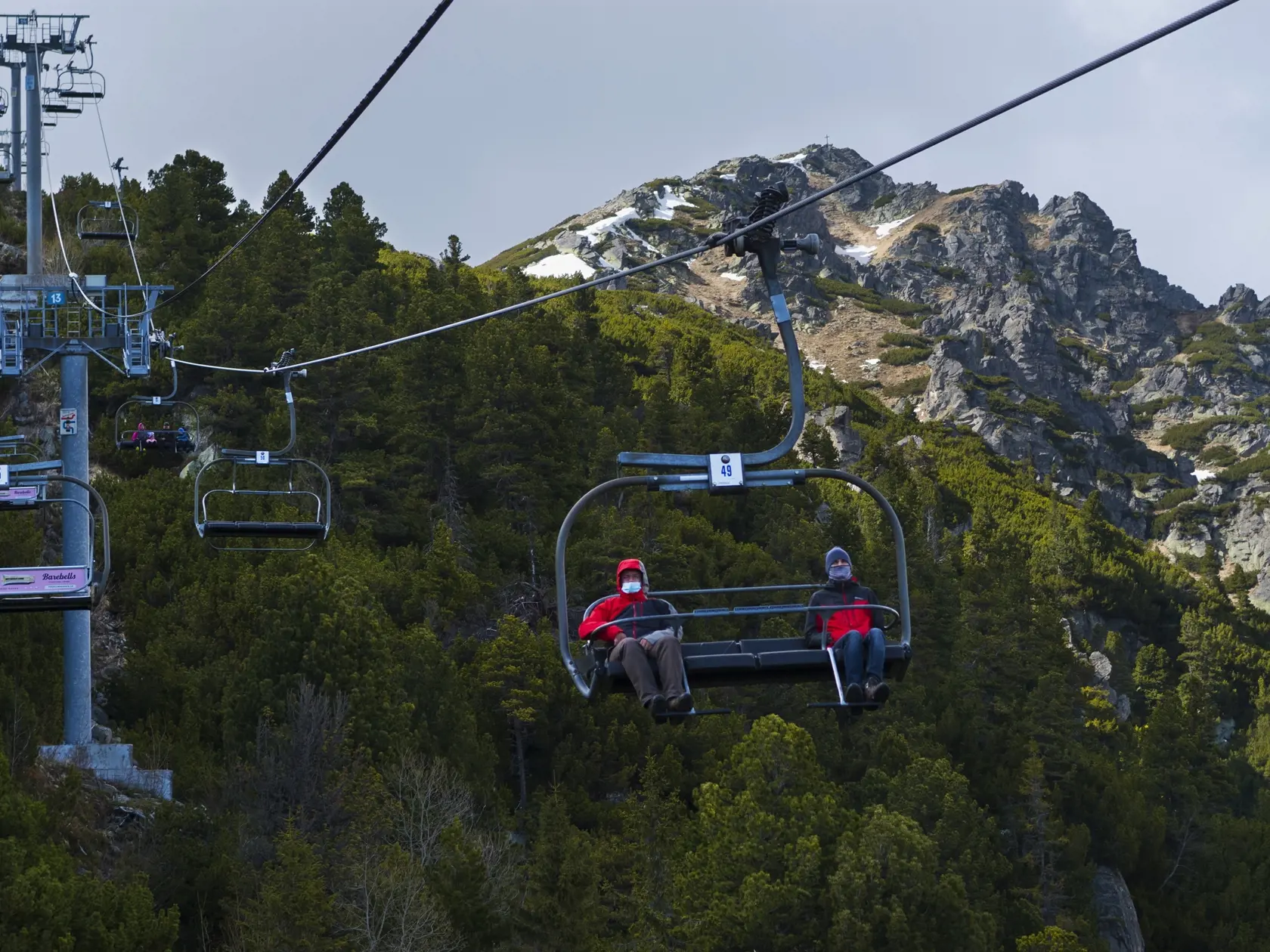 Lanovka zo Štrbského Plesa na Solisko začala letnú prevádzku pre peších turistov v máji. Na snímke turisti na sedačke lanovky zo Štrbského plesa na Solisko, hore sa týči vrchol Predného Soliska s osadeným krížom. Štrbské Pleso, 3. mája 2020 FOTO