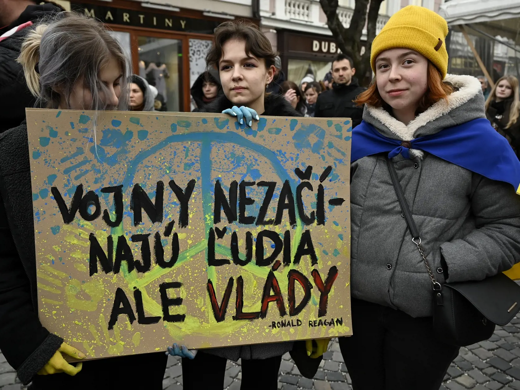 Študentky s transparentom sledujú koncert Trenčín pre Ukrajinu v Trenčíne, 3. marca 2022. Podujatie v Trenčíne je prvým zo série siedmich Koncertov pre Ukrajinu, ktoré skoordinovala Hudobná únia Slovenska. V nedeľu 6. marca budú nasledovať koncerty v Prešove, Košiciach, Banskej Bystrici, Žiline, Trnave a Nitre. FOTO TASR - Radovan Stoklasa