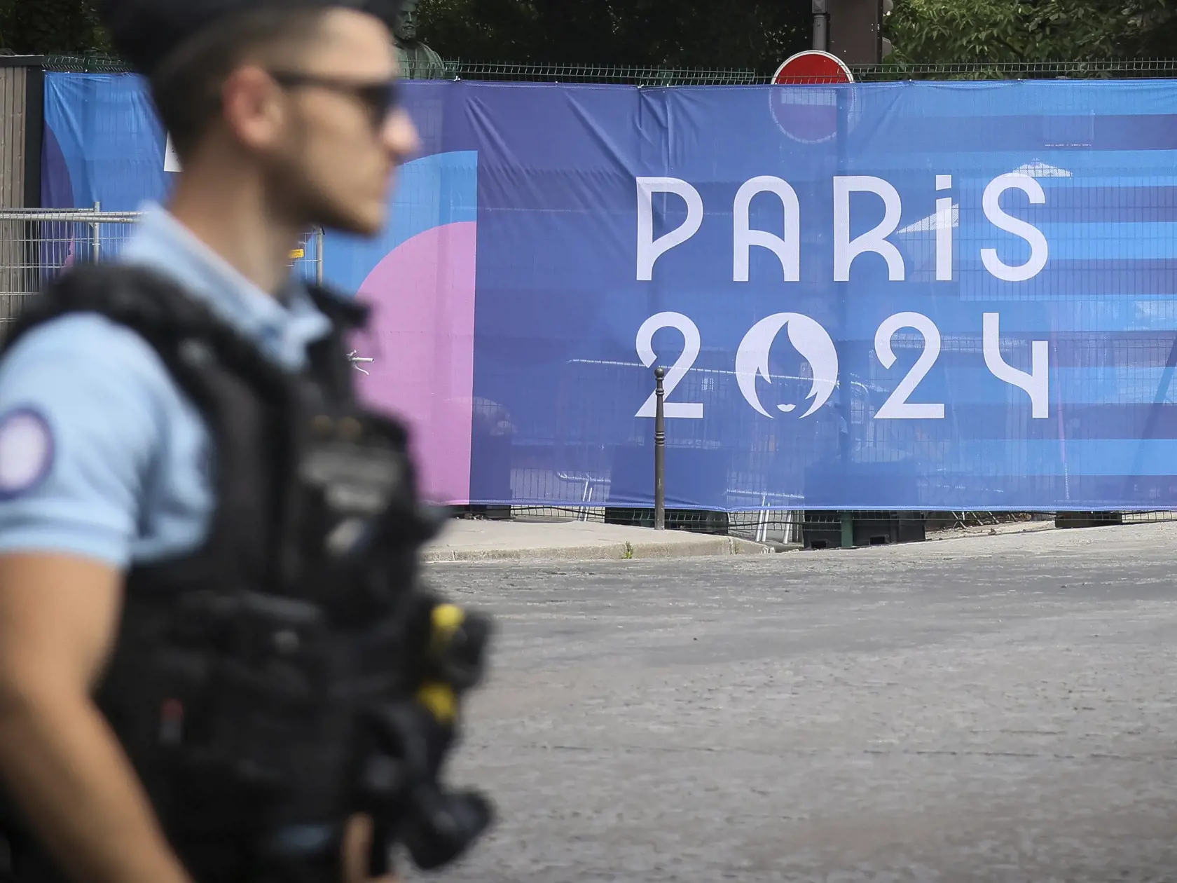 Policajt kráča okolo plachty s nápisom Paríž 2024 pred XXIII. letnými olympijskými hrami v Paríži 20. júla 2024. Letné olympijské hry sa budú vo francúzskej metropole konať od 26. júla do 11. augusta 2024.
