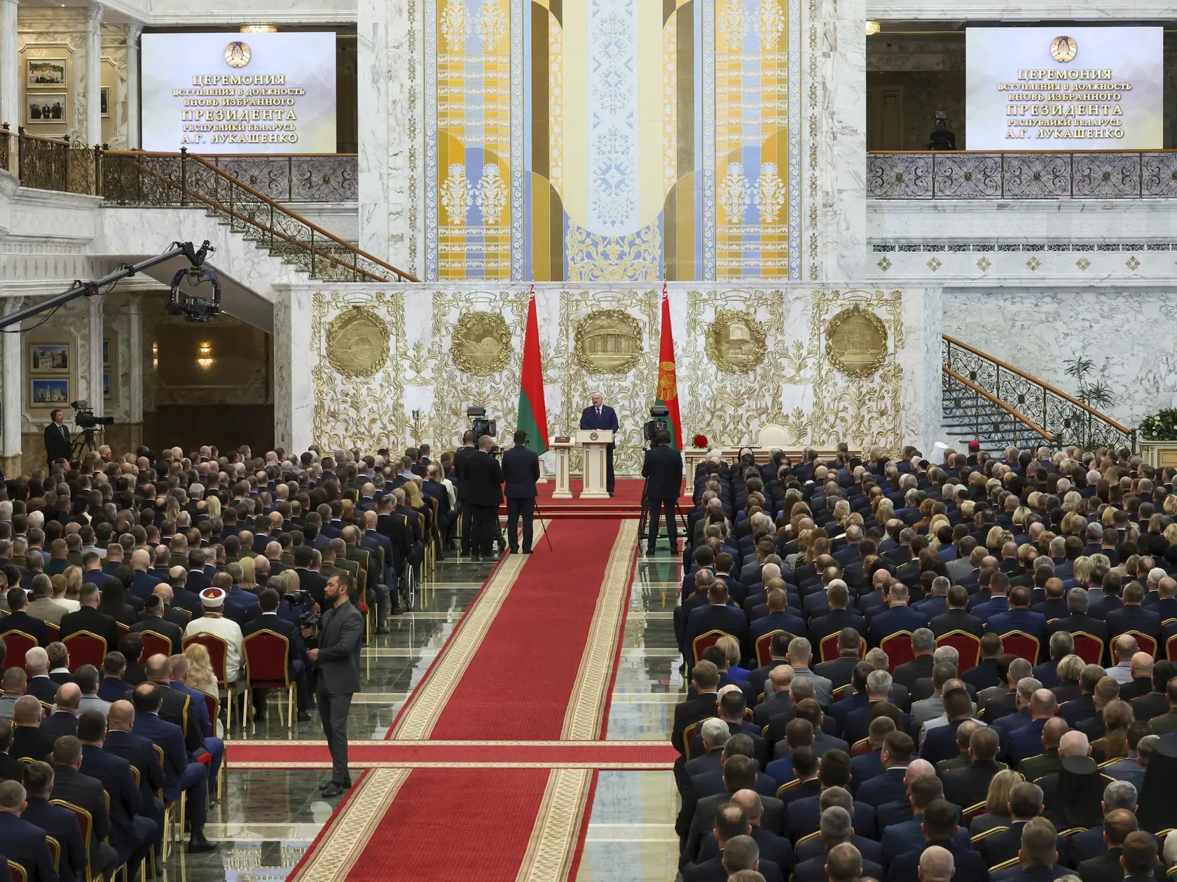 Na snímke ľudia sledujú, ako bieloruský prezident Alexandr Lukašenko skladá sľub počas jeho inaugurácie v Minsku 25. marca 2025.