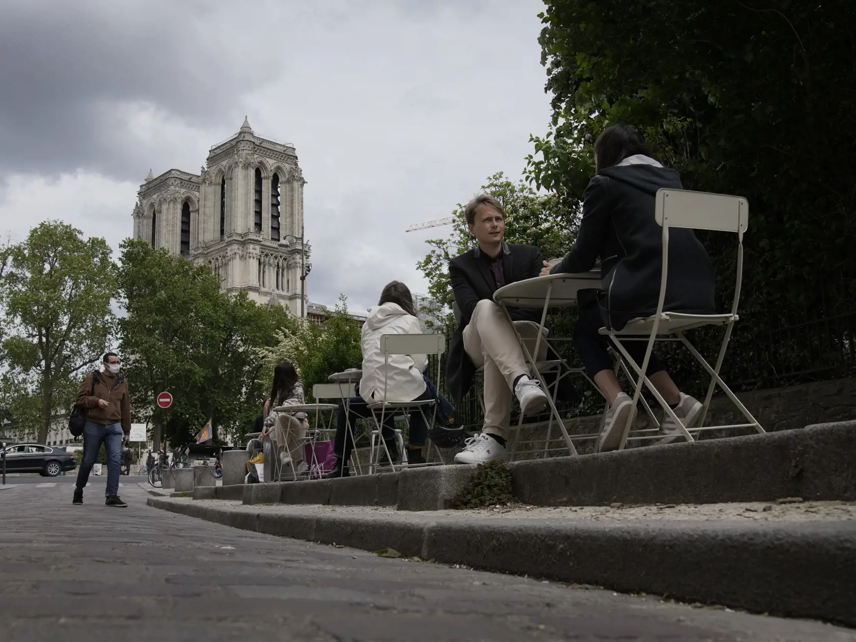 Ľudia sedia na terase reštaurácie pred katedrálou Notre-Dame v Paríži.