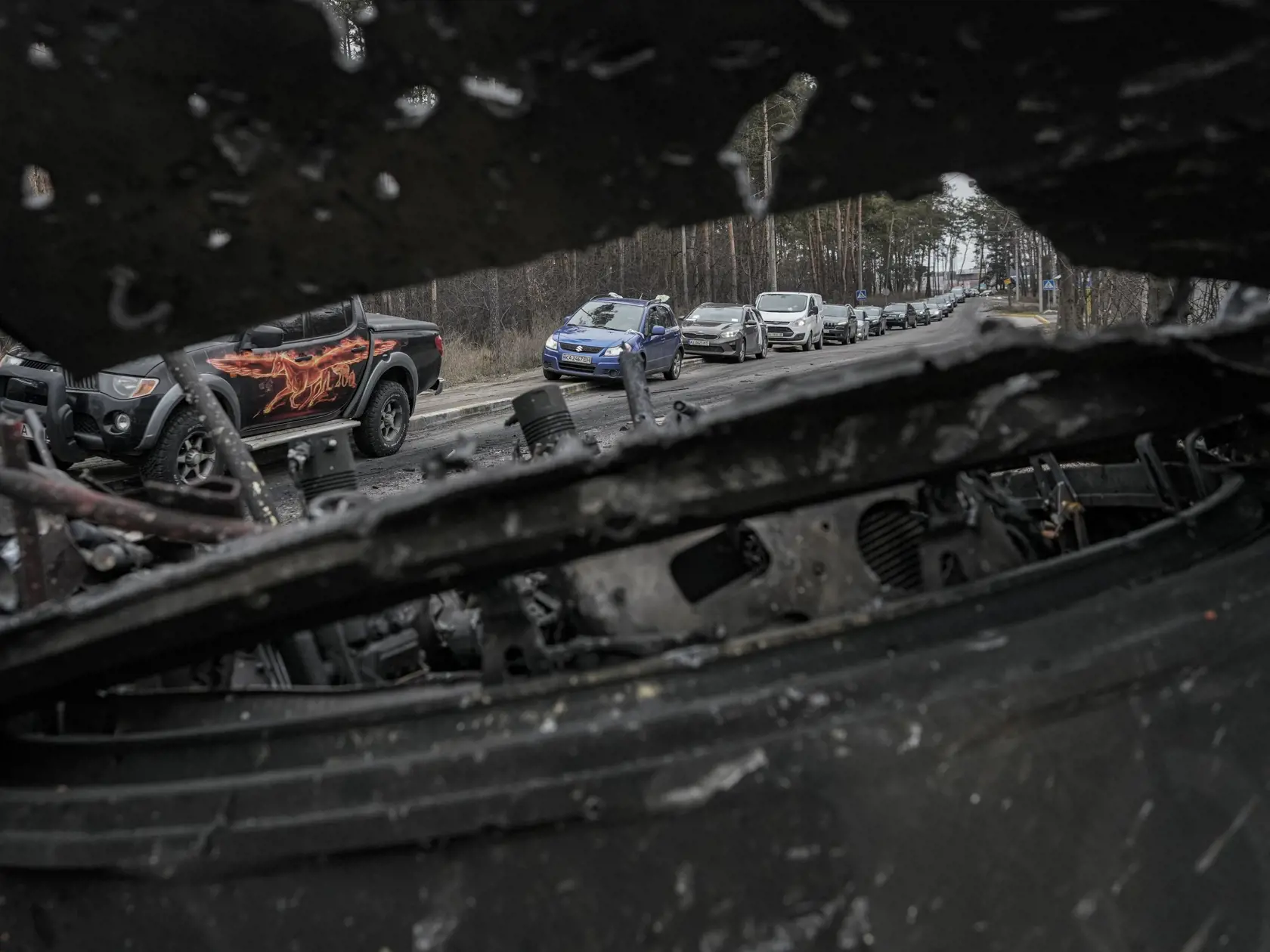 KK7 Irpiň - Pohľad cez zničený ruský tank na autá počas evakuácie civilistov z mesta Irpiň na okraji Kyjeva v štrnásty deň ruskej invázie na Ukrajine v stredu 9. marca 2022. FOTO TASR/AP 
 
Cars drive past a destroyed Russian tank as a convoy of vehicles evacuating civilians leaves Irpin, on the outskirts of Kyiv, Ukraine, Wednesday, March 9, 2022. A Russian airstrike devastated a maternity hospital Wednesday in the besieged port city of Mariupol amid growing warnings from the West that Moscow's