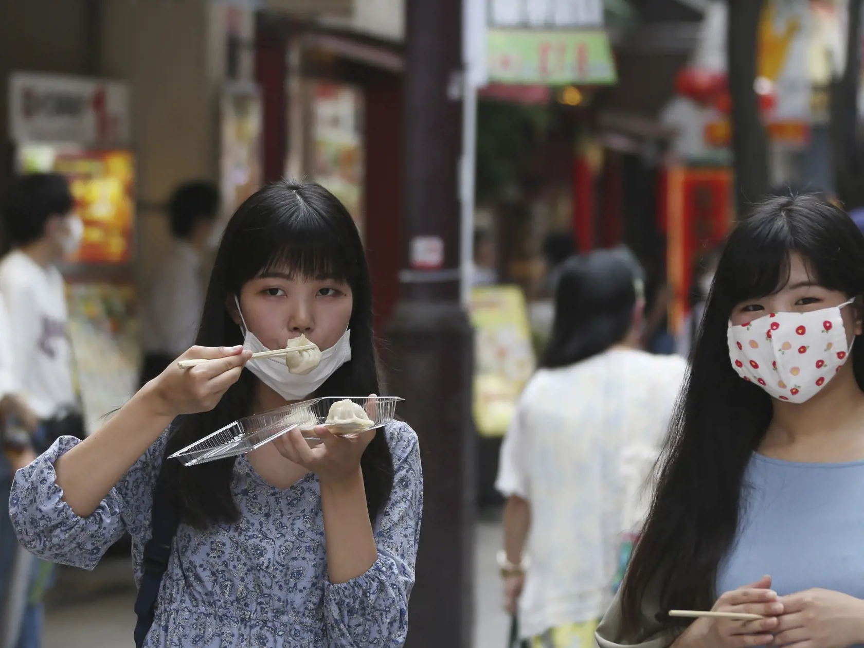 EBE 12 Jokohama - Na snímke dievča so zveseným rúškom je pirohy na ulici v čínskej štvrti v Jokohame pri Tokiu v Japonsku v piatok 24. júla 2020. FOTO TASR/AP
People wearing face masks to protect against the spread of the new coronavirus eat dumplings in Chinatown in Yokohama, near Tokyo, Friday, July 24, 2020. (AP Photo/Koji Sasahara)