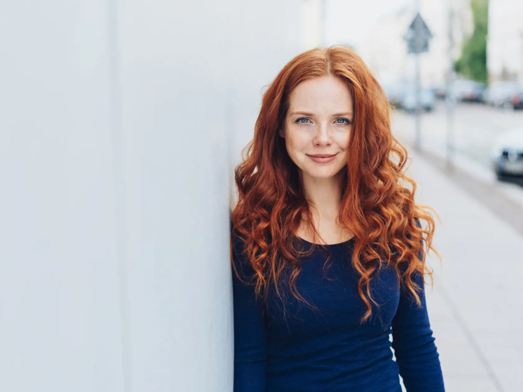 Friendly,Attractive,Young,Redhead,Woman,Relaxing,Leaning,Against,A,White
