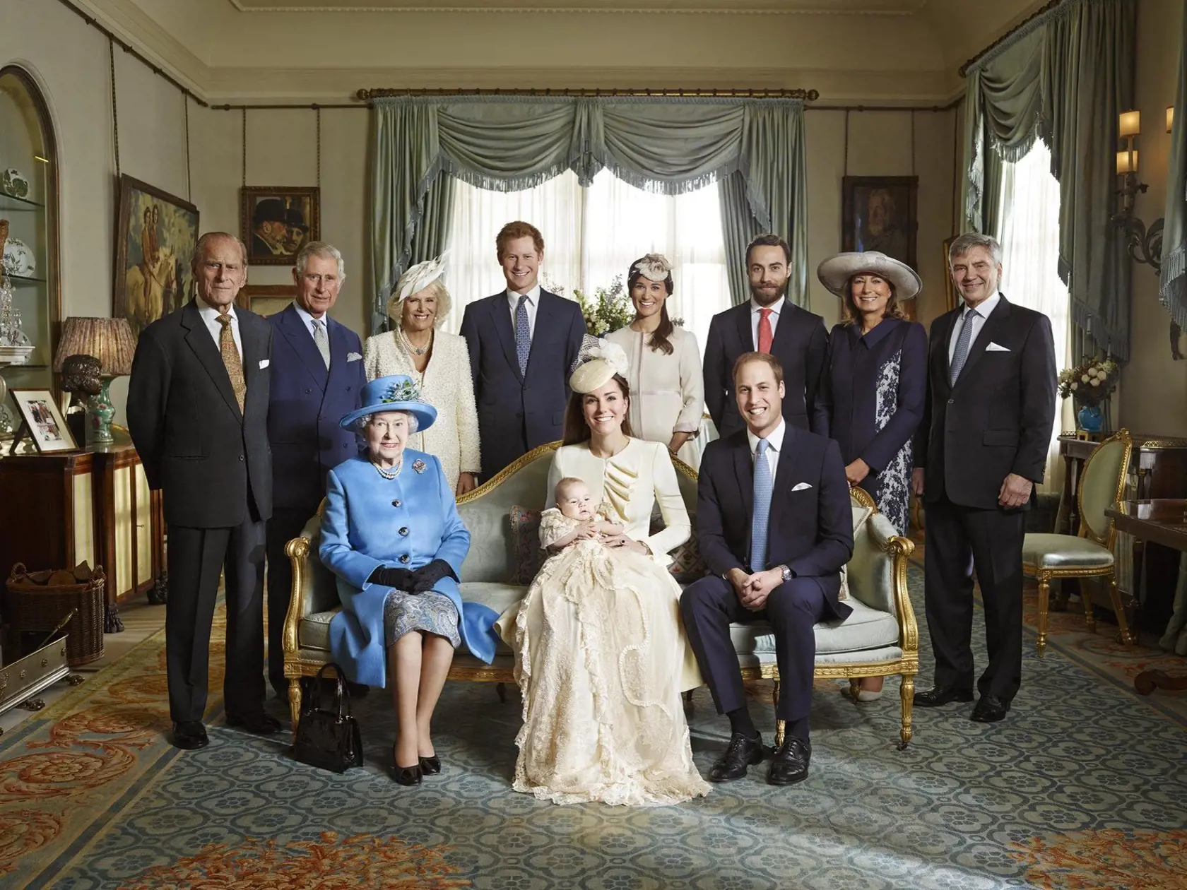 Vojvodkyňa Kate s malým Georgeom sedí medzi Williamom a kráľovnou Alžbetou. Horný rad zľava: Princ Philip, princ Charles a vojvodkyňa z Cornwallu, princ Harry, Pippa Middleton, James Middleton, Carole Middleton a Michael Middleton.
