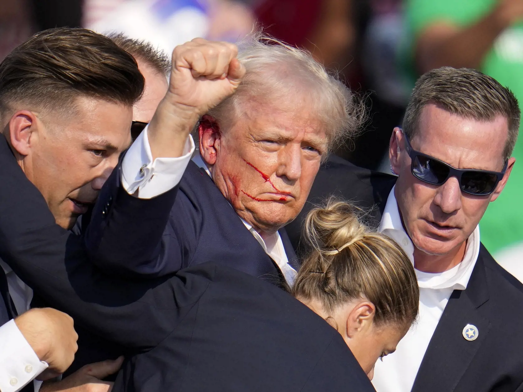 Republikánsky prezidentský kandidát Donald Trump reaguje pri odchode za pomoci ochrankárov z predvolebného mítingu v meste Butler v americkom štáte Pensylvánia 13. júla 2024. Trump potvrdil, že v sobotu na mítingu v Pensylvánii ho zasiahla guľka. Tá mu prestrelila hornú časť pravého ucha. Bývalý americký prezident sa vyjadril na sociálnej sieti, informuje TASR.