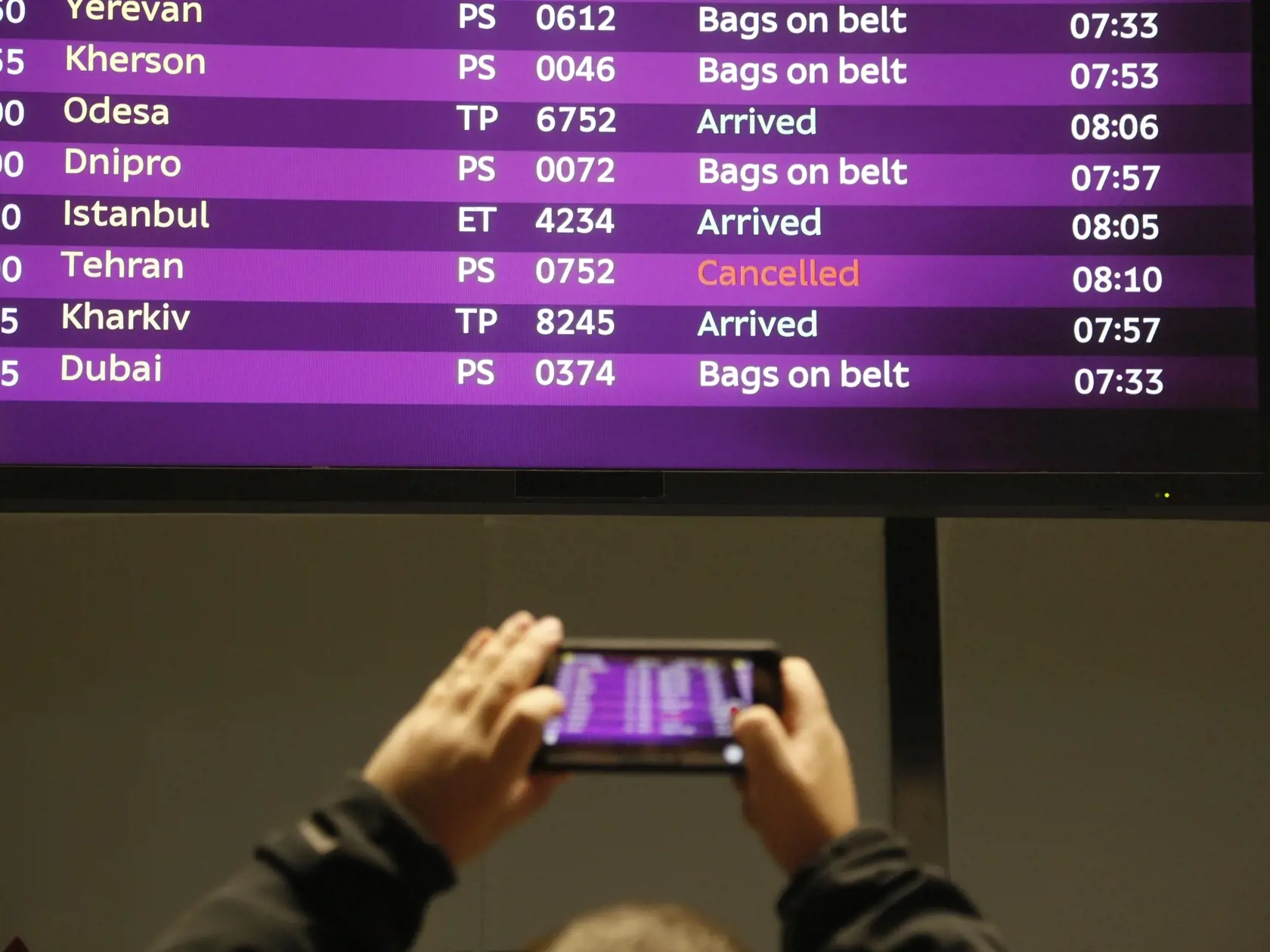 KK14 Kyjev - Muž si fotografuje tabuľu s príletmi a zrušeným letom z Teheránu po havárii ukrajinského lietadla typu Boeing 737-800 reaguje na medzinárodnom letisku v Kyjeve 8. januára 2020. Haváriu lietadla ukrajinských aerolínií so 180 ľuďmi na palube, ktoré sa v stredu zrútilo v iránskej metropole Teherán, nikto neprežil. Lietadlo typu Boeing 737-800 spoločnosti Ukraine International Airlines (UIA) smerujúce do ukrajinskej metropoly Kyjev sa zrútilo na predmestí Teheránu krátko po vzlete z Med