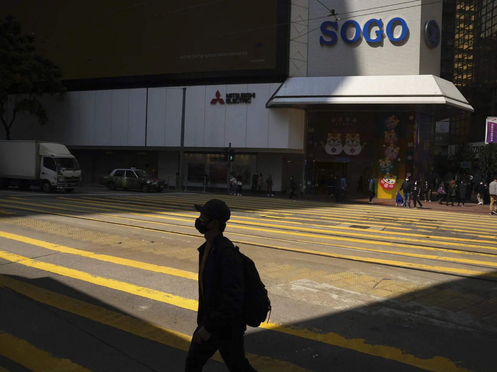 Muž s ochranným rúškom kráča po ulici Causeway Bay, v obchodnej štvrti v Hongkongu 25. februára 2022. Hongkonská vláda vo štvrtok uplatnila mimoriadne právomoci, aby umožnila lekárom a zdravotným sestrám z iných oblastí Číny pôsobiť v tomto meste, ktoré aktuálne zápasí s prudkým nárastom počtu nakazených koronavírusom.