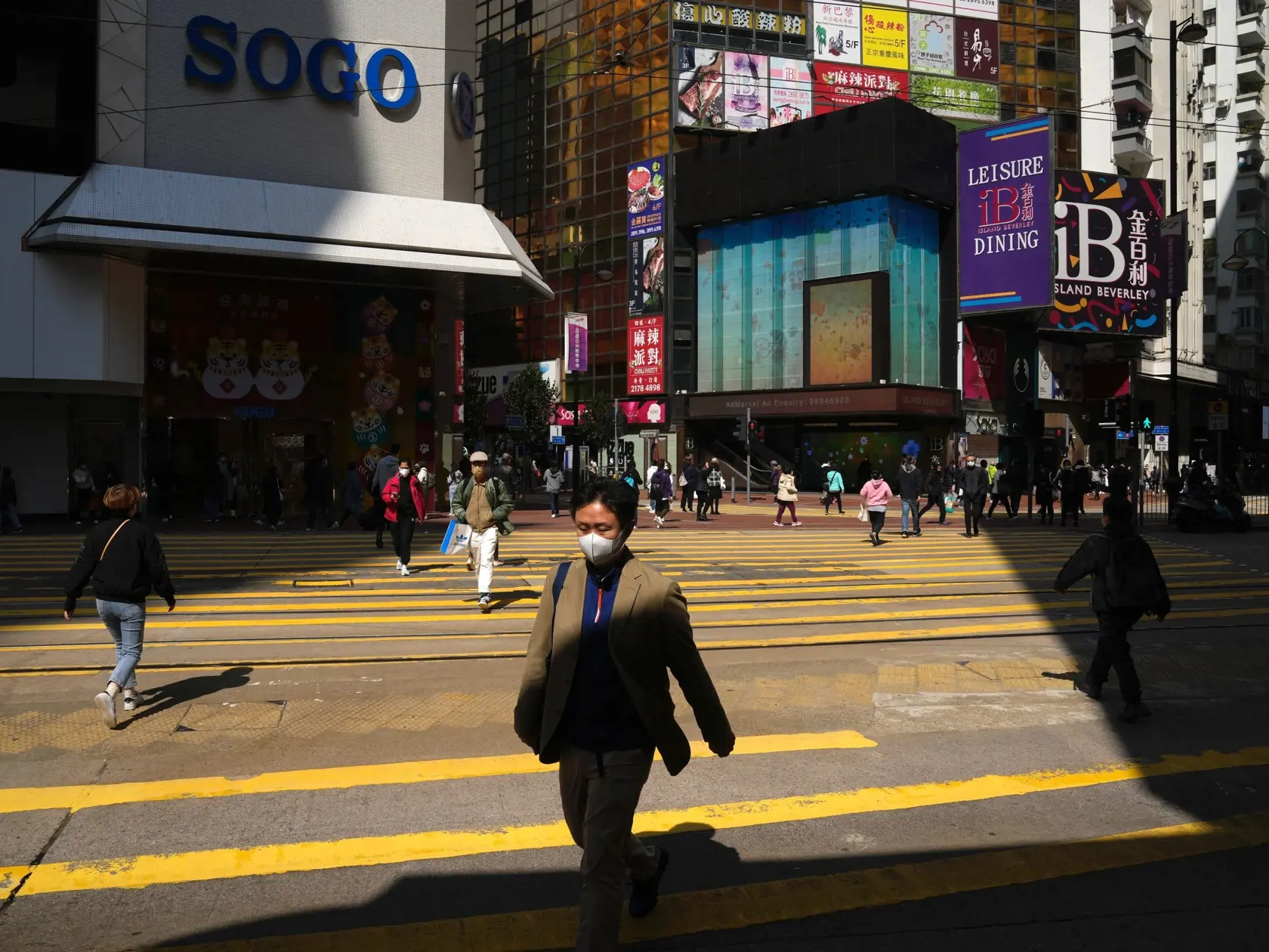 Muž s ochranným rúškom kráča po ulici Causeway Bay, v obchodnej štvrti v Hongkongu 25. februára 2022.