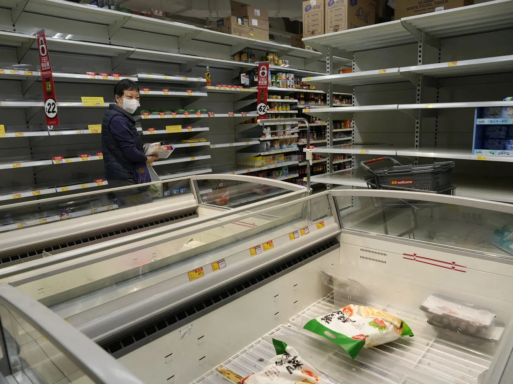 Žena prechádza okolo prázdnych regálov a mraziacich boxov, keďže obyvatelia znepokojení možným nedostatkom si robia zásoby potravín v supermarkete v Hongkongu vo štvrtok 3. marca 2022. Nové prípady nakazených koronavírusom tu stále pribúdajú a zdravotnícke úrady uviedli, že vláda môže zaviesť nové protipandemické opatrenia.