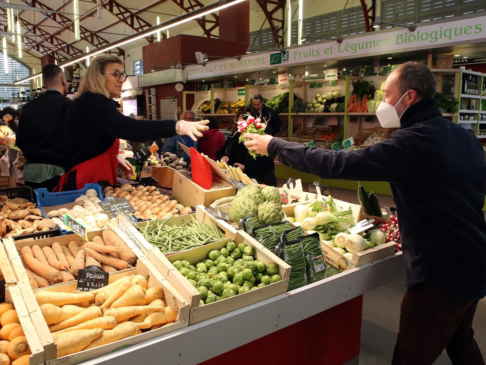 Zákazník s respirátorom kupuje reďkovky na tržnici vo francúzskom kúpeľnom meste Biarritz, ktoré sa nachádza asi 18 kilometrov severne od hraníc so Španielskom v pondelok 14. marca 2022. Francúzi už nepotrebujú na vstup do interiérov rúška ani covid pasy. V krajine prestala v pondelok platiť väčšina zostávajúcich protiepidemických opatrení.