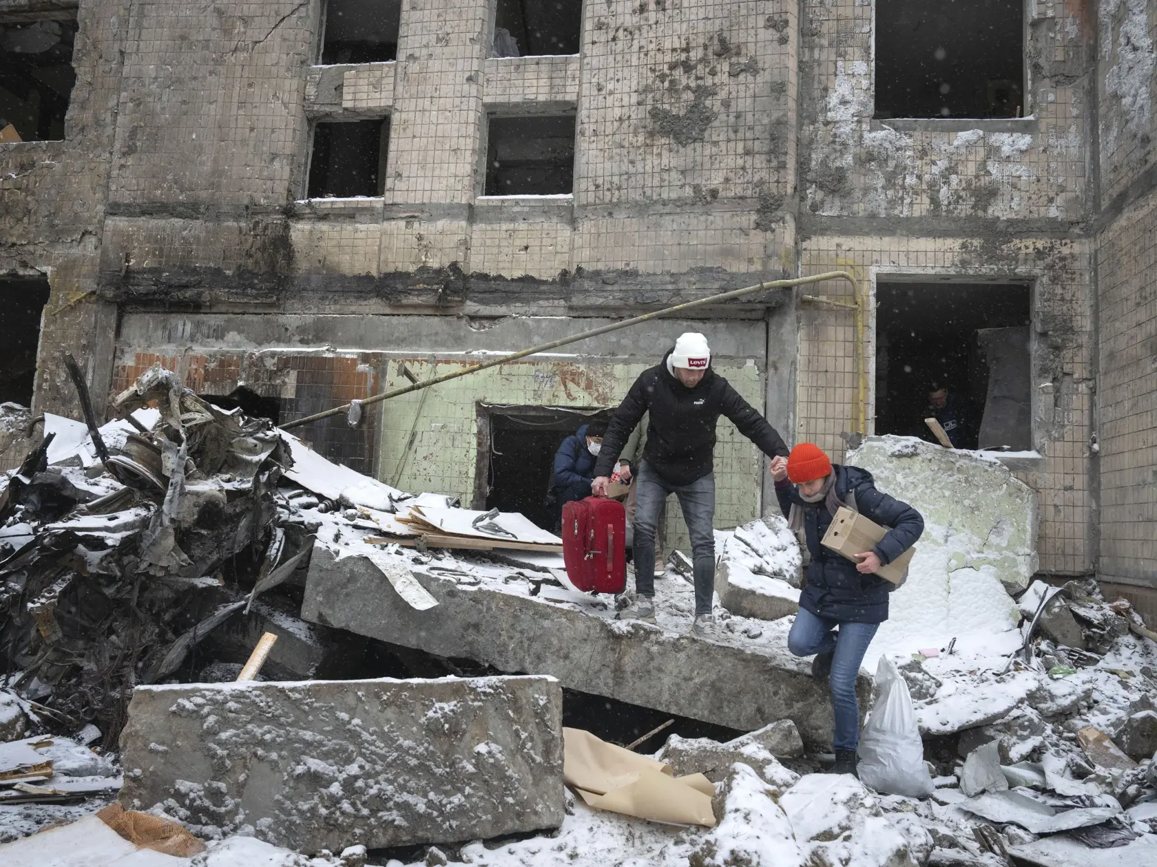 Ľudia odnášajú svoje osobné veci z obytného domu, ktorý zničil utorňajší raketový útok ruskej armády v ukrajinskej metropole Kyjev v stredu 3. januára 2024.