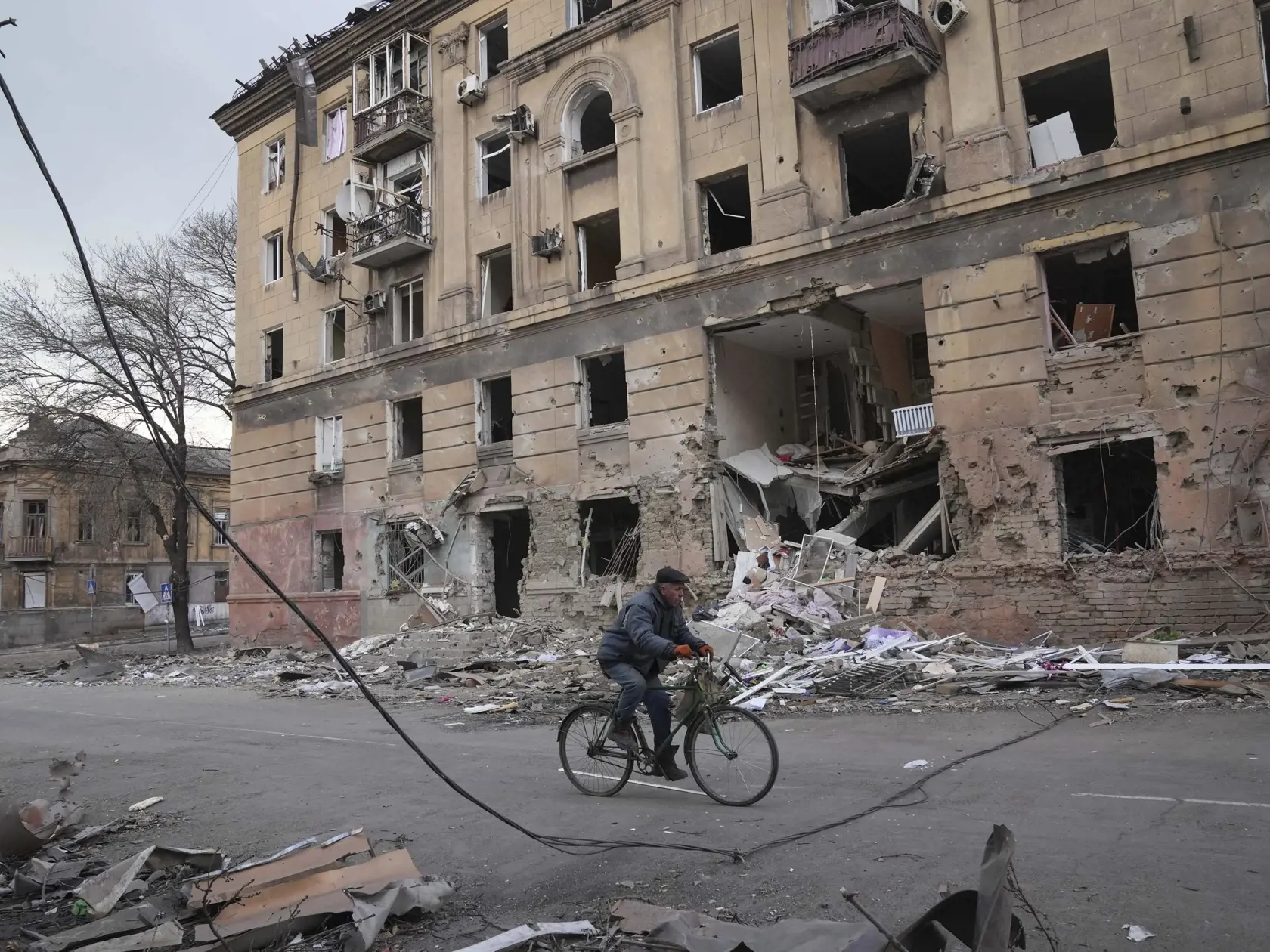 KK59 Mariupol - Na snímke muž jazdí na bicykli okolo budovy po ostreľovaní v Mariupole počas štrnásteho dňa ruskej invázie na Ukrajine v stredu 9. marca 2022. Ruská armáda pri stredajšom ostreľovaní ukrajinského mesta Mariupol zasiahla a zničila detskú nemocnicu a pôrodnicu, tvrdia miestni činitelia aj ukrajinský prezident Volodymyr Zelenskyj. TASR túto informáciu prevzala zo stanice Sky News. FOTO TASR/AP  

A man rides a bicycle in front of a damaged by shelling apartment building in Mariupol,