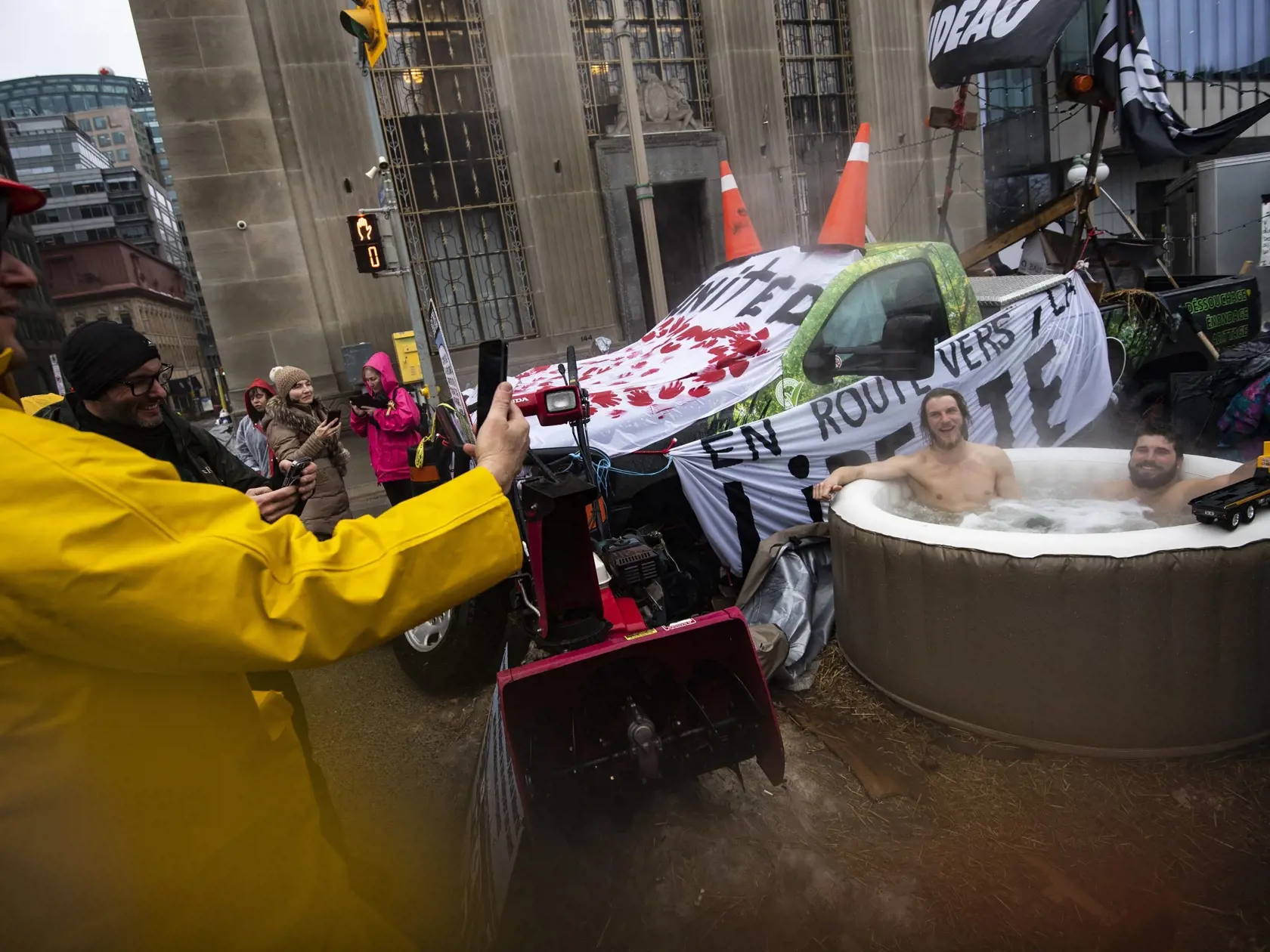 WA 3 Ottawa - Ľudia si fotia demonštrantov sediacich v nafukovacom bazéne s horúcou vodou počas pokračujúcich protestov vodičov kamiónov proti pandemickým opatreniam v Ottawe vo štvrtok 17. februára 2022. Kanadská polícia zatkla v piatok  namenej 70 protestujúcich kamionistov. Sériu demonštrácií spustili kanadskí kamionisti 22. januára, keď žiadali zrušenie povinného očkovania proti koronavírusu, ktoré je v Kanade nutné pri návrate z USA. Ich požiadavky však teraz zahŕňajú zrušenie všetkých opat