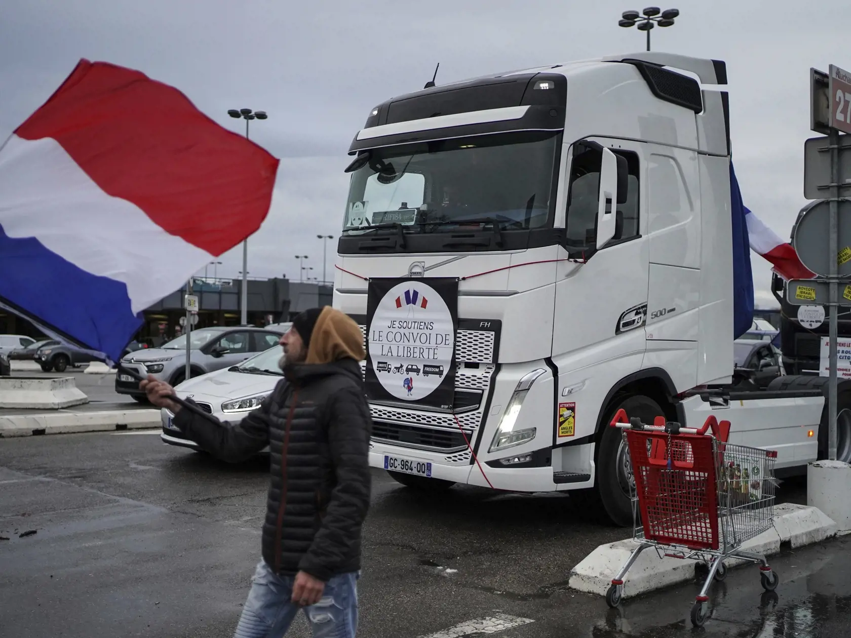 PK 35 Lyon - Demonštrant máva vlajkou pred konvojom v Lyone v piatok 11. februára 2022. Do Paríža prichádzali v piatok z celého Francúzska stovky vozidiel na protest proti epidemiologickým opatreniam vlády. Napriek varovaniu polície, ktorá pre protest zmobilizovala tisícky svojich príslušníkov, ako aj obrnené transportéry a vodné delá, mnohí z demonštrantov dúfajú, že sa im podarí francúzske hlavné mesto zablokovať. FOTO TASR/AP

A protester waves a French flag next to a truck taking part in a c
