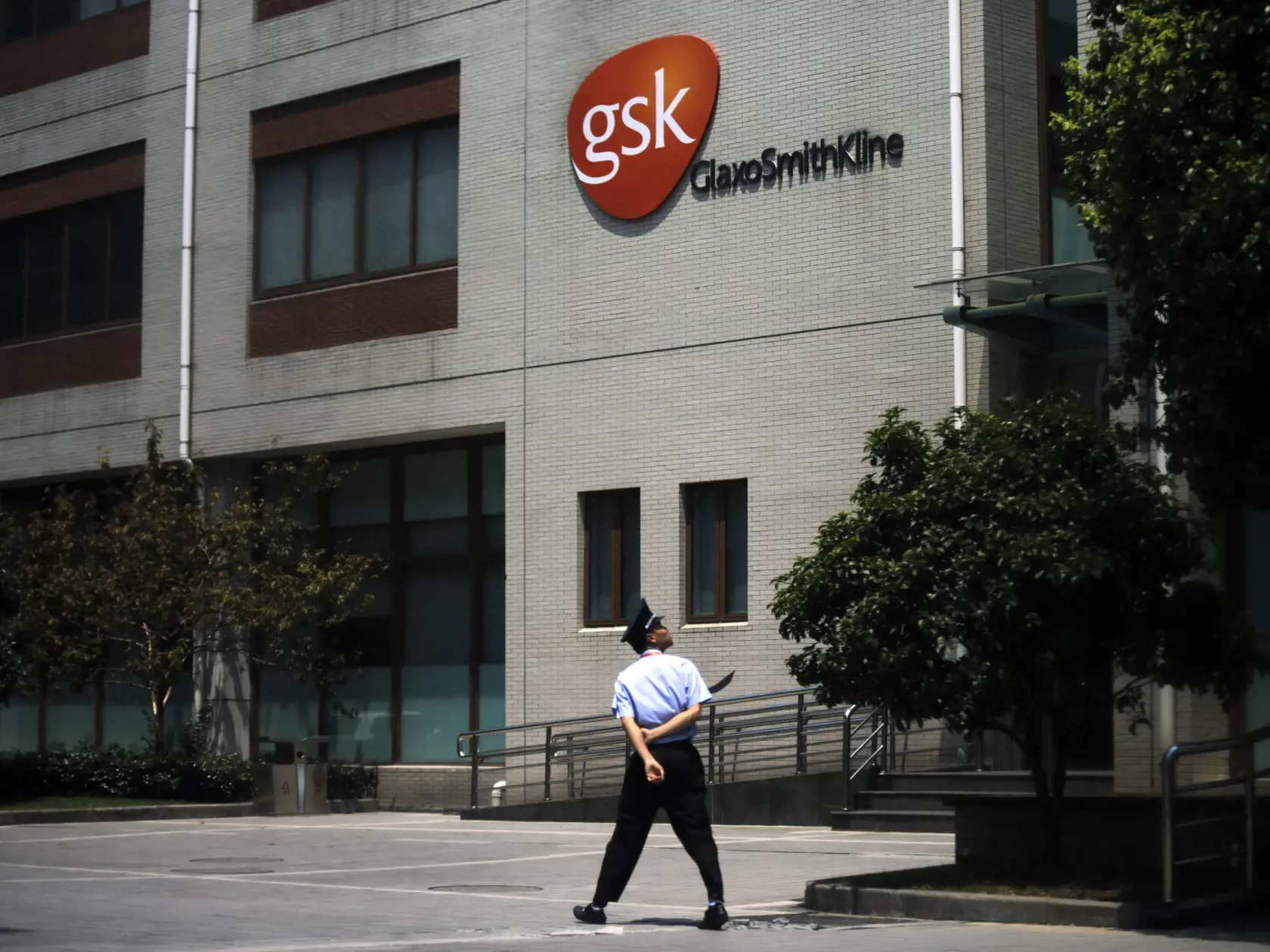 KK33 Šanghaj - Na archívnej snímke z 24. júla 2013 budova farmaceutickej firmy GlaxoSmithKline v Šanghaji. Britská farmaceutická firma GlaxoSmithKline a nemecká biotechnologická spoločnosť CureVac v stredu 3. februára 2021 oznámili, že začali spoločne vyvíjať novú vakcínu, ktorá potenciálne poskytne imunitu voči viacerým variantom koronavírusu SARS-CoV-2. FOTO TASR/AP
FILE - In this file photo dated Wednesday, July 24, 2013, a security guard walks in front of the GlaxoSmithKline building in Sha
