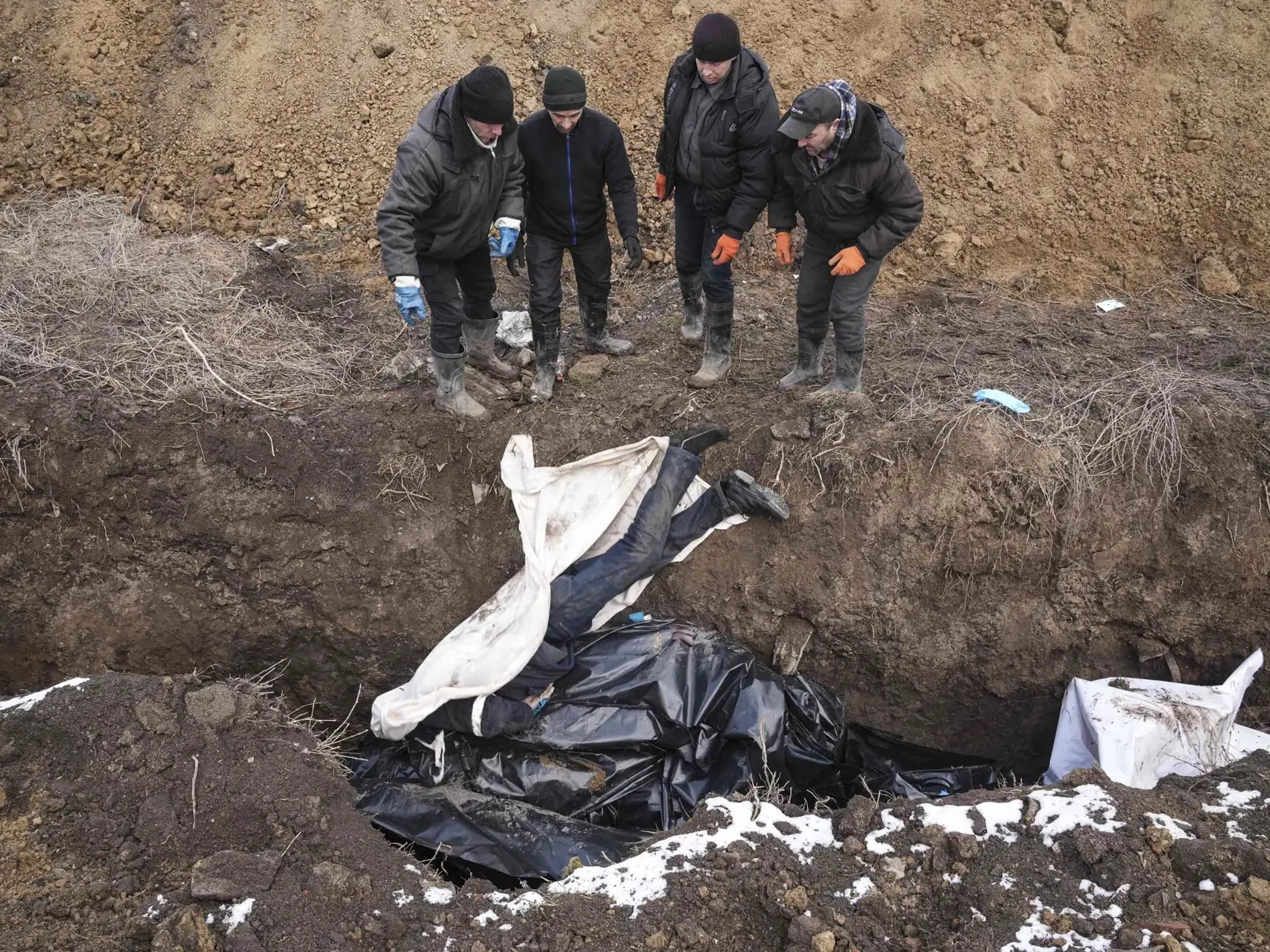 WA 18 Mariupol - Na snímke mŕtve telá ukladujú do masového hrobu v Mariupole počas štrnásteho dňa ruskej invázie na Ukrajine v stredu 9. marca 2022. FOTO TASR/AP