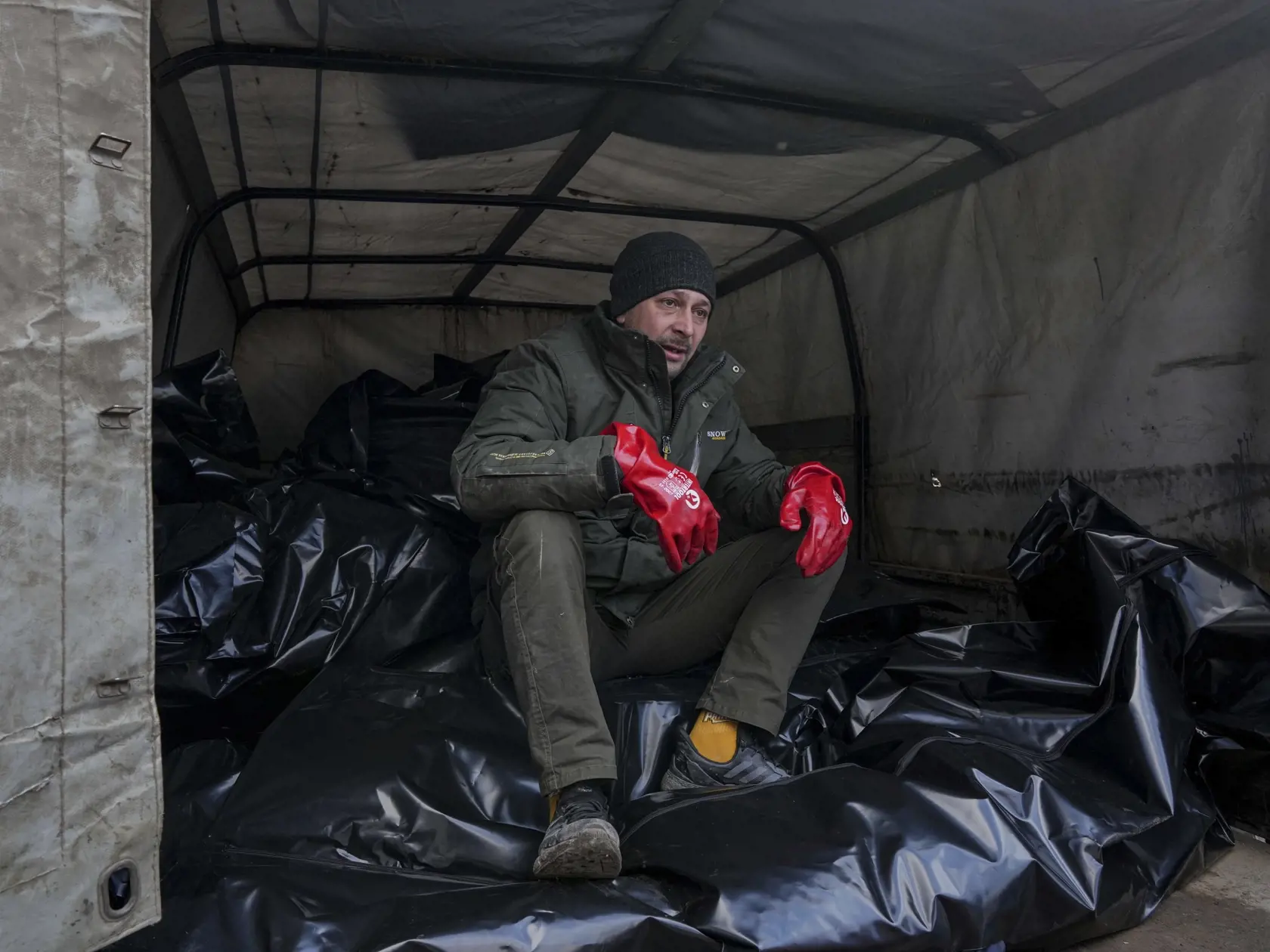 WA 19 Mariupol - Zamestnanec pohrebnej služby sedí na vreciach s telami obetí pred ich uložením do masového hrobu v Mariupole počas štrnásteho dňa ruskej invázie na Ukrajine v stredu 9. marca 2022. FOTO TASR/AP