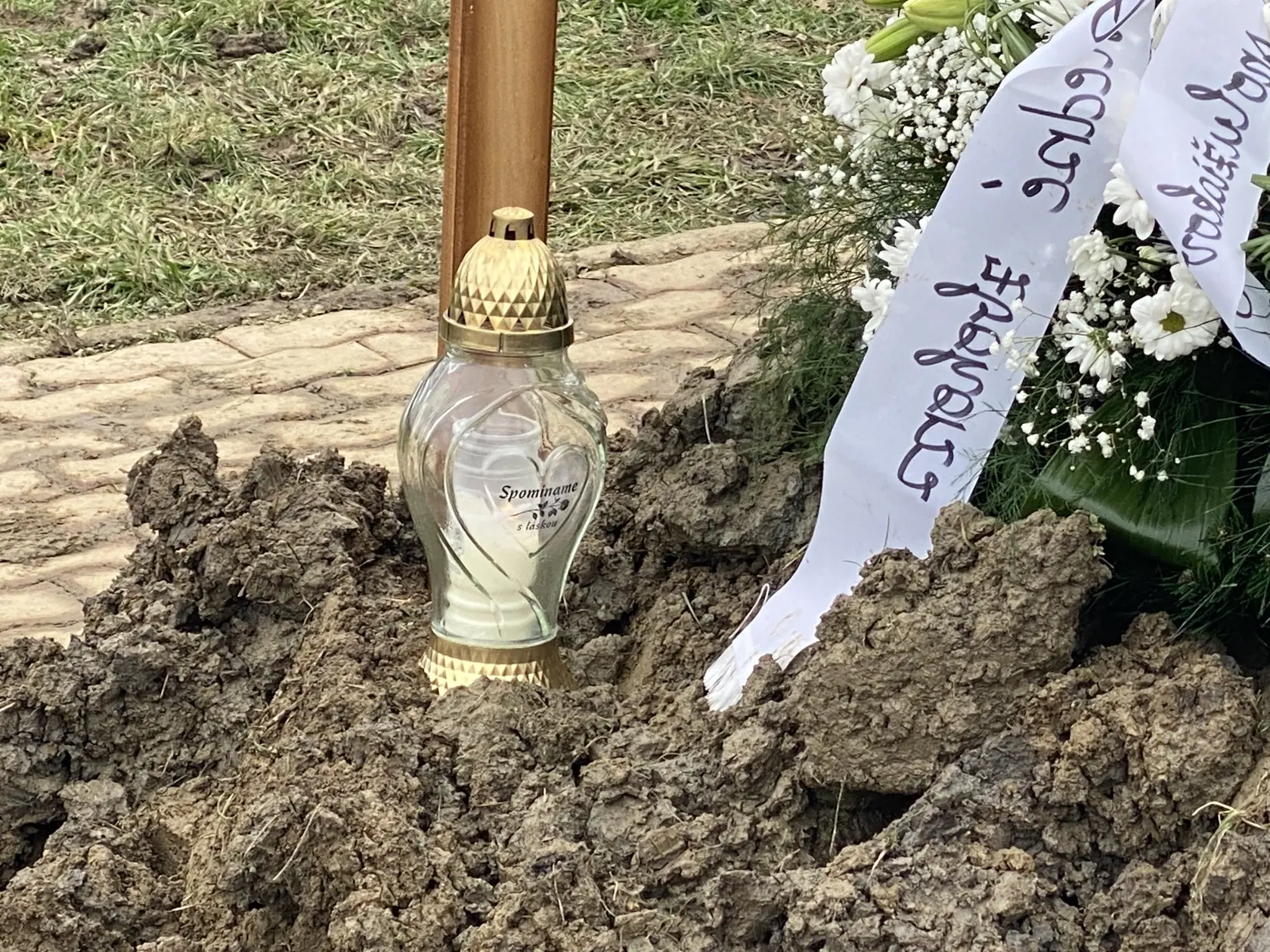 Na hrobe svietia sviečky vo viacerých kahancoch, na jednom z nich je nápis: Spomíname s láskou.