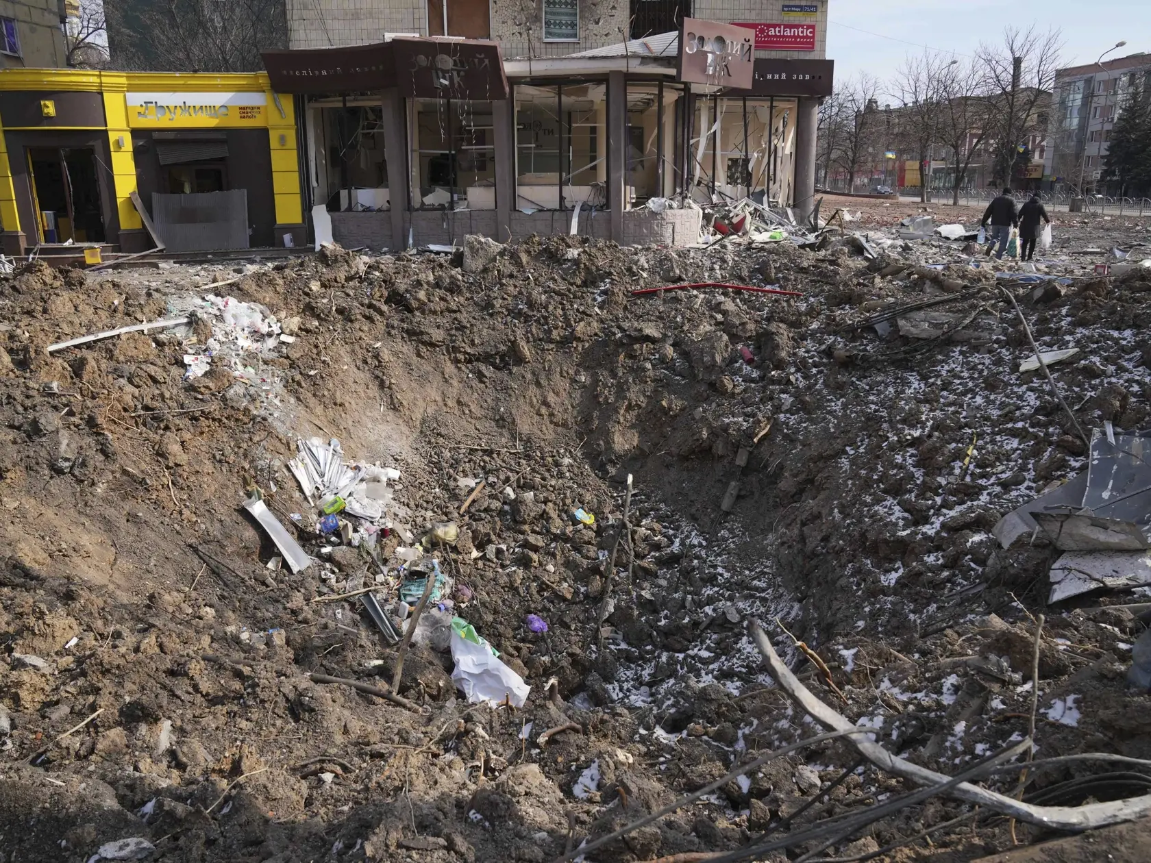 KK40 Mariupol - Ľudia kráčajú okolo krátera z výbuchu v prístavnom meste Mariupol na juhovýchode Ukrajiny počas 18. dňa ruskej invázie na Ukrajine v nedeľu 13. marca 2022. TASR/AP