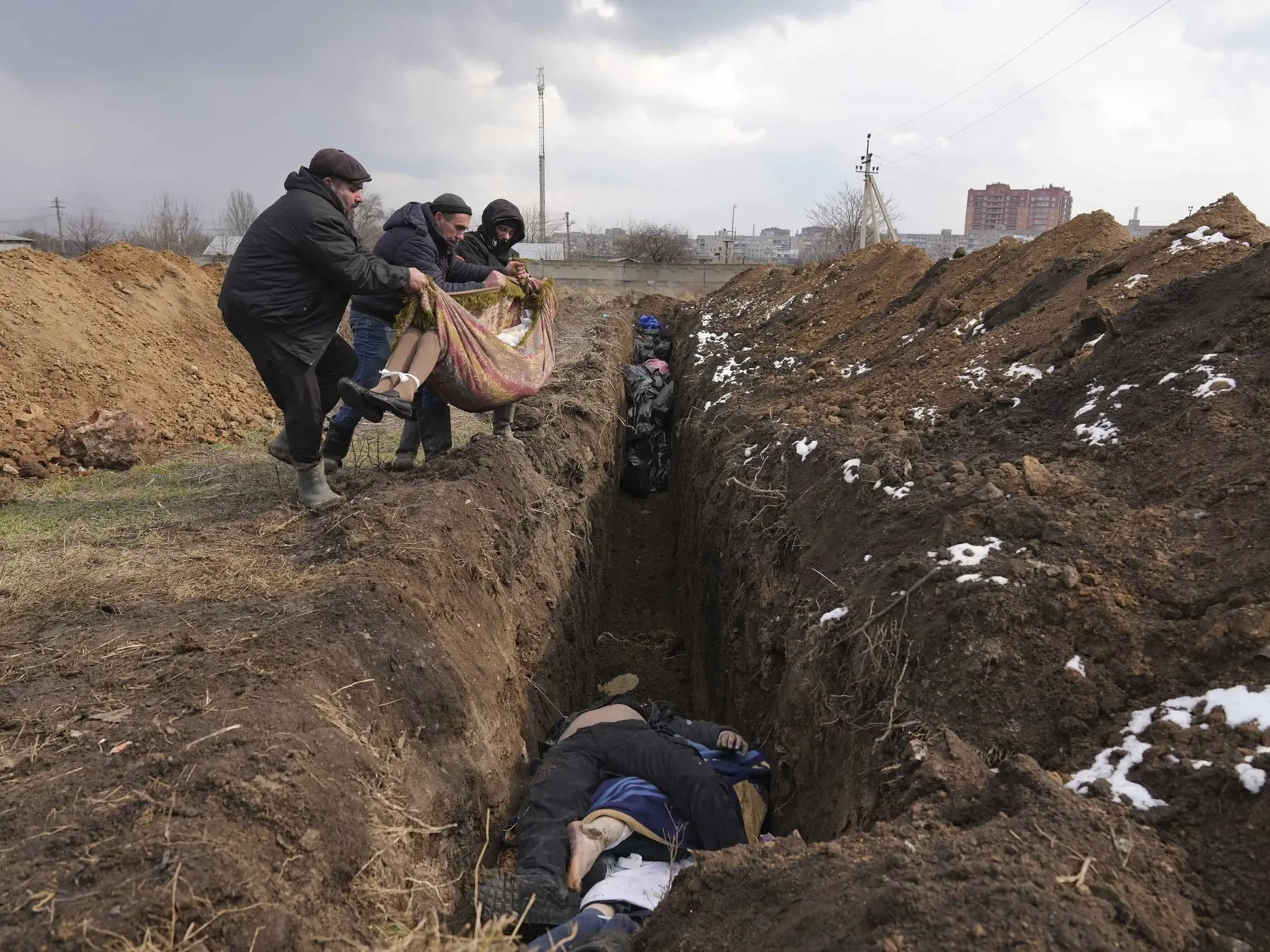 WA 17 Mariupol - Na snímke mŕtve telá ukladujú do masového hrobu v Mariupole počas štrnásteho dňa ruskej invázie na Ukrajine v stredu 9. marca 2022. FOTO TASR/AP