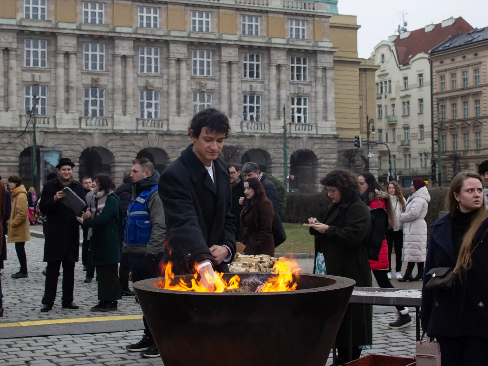 Na snímke chlapec prikladá polienko do pietneho ohňa za obete streľby na Filozofickej fakulte Univerzity Karlovej v Prahe. Praha, 30. januára 2024.