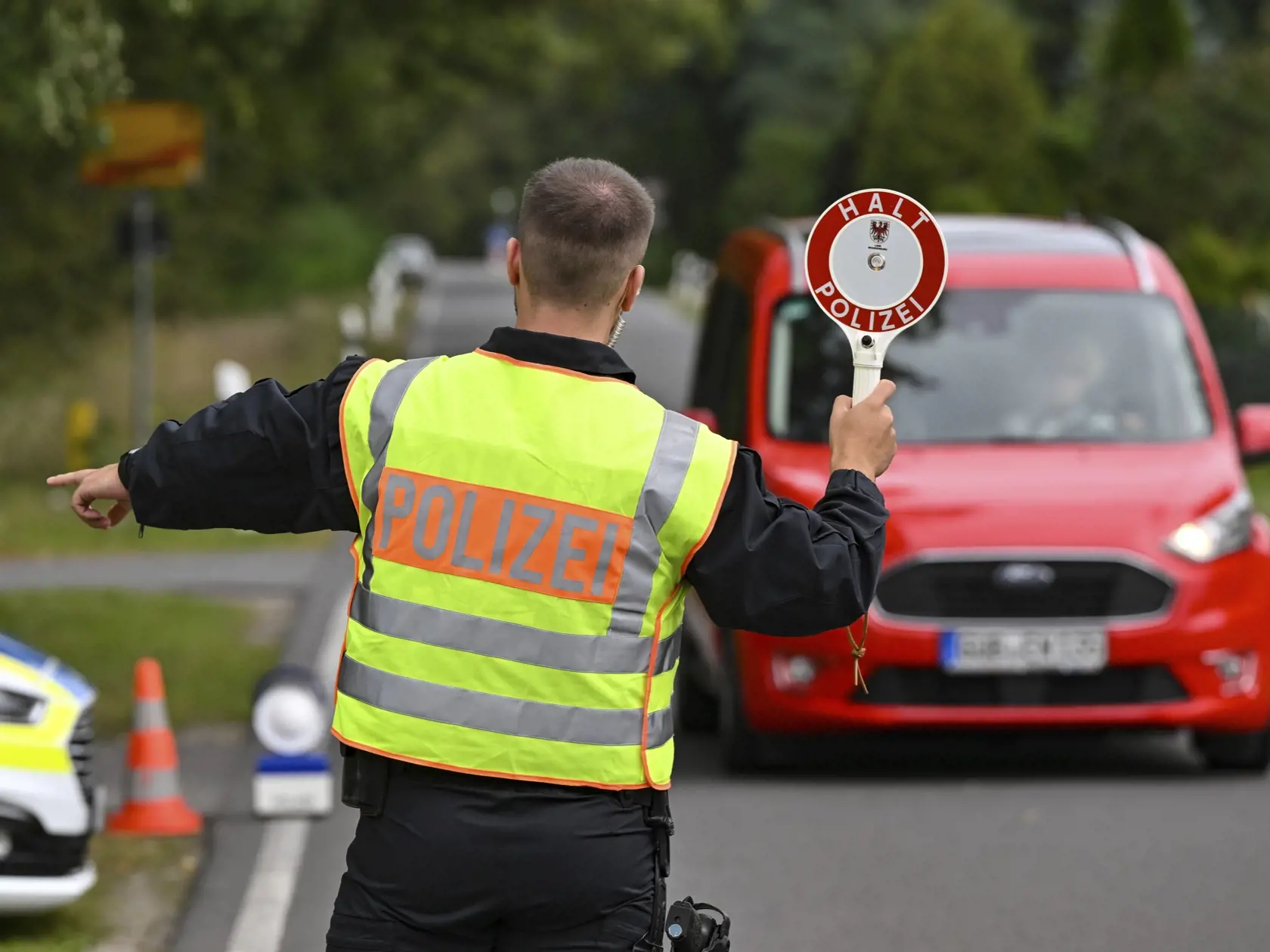Policajt zastavuje počas pollcajnej akcie zameranej a boj proti nelegálnej migrácii a činnosti prevádzačských gangov v nemeckom Roggosene v pondelok 25. septembra 2023. Nemecká polícia od utorkových skorých ranných hodín prehľadávala byty a domy na území piatich spolkových krajín, prevažne na severe krajiny. Razie boli zamerané na boj proti nelegálnej migrácii a činnosti prevádzačských gangov.